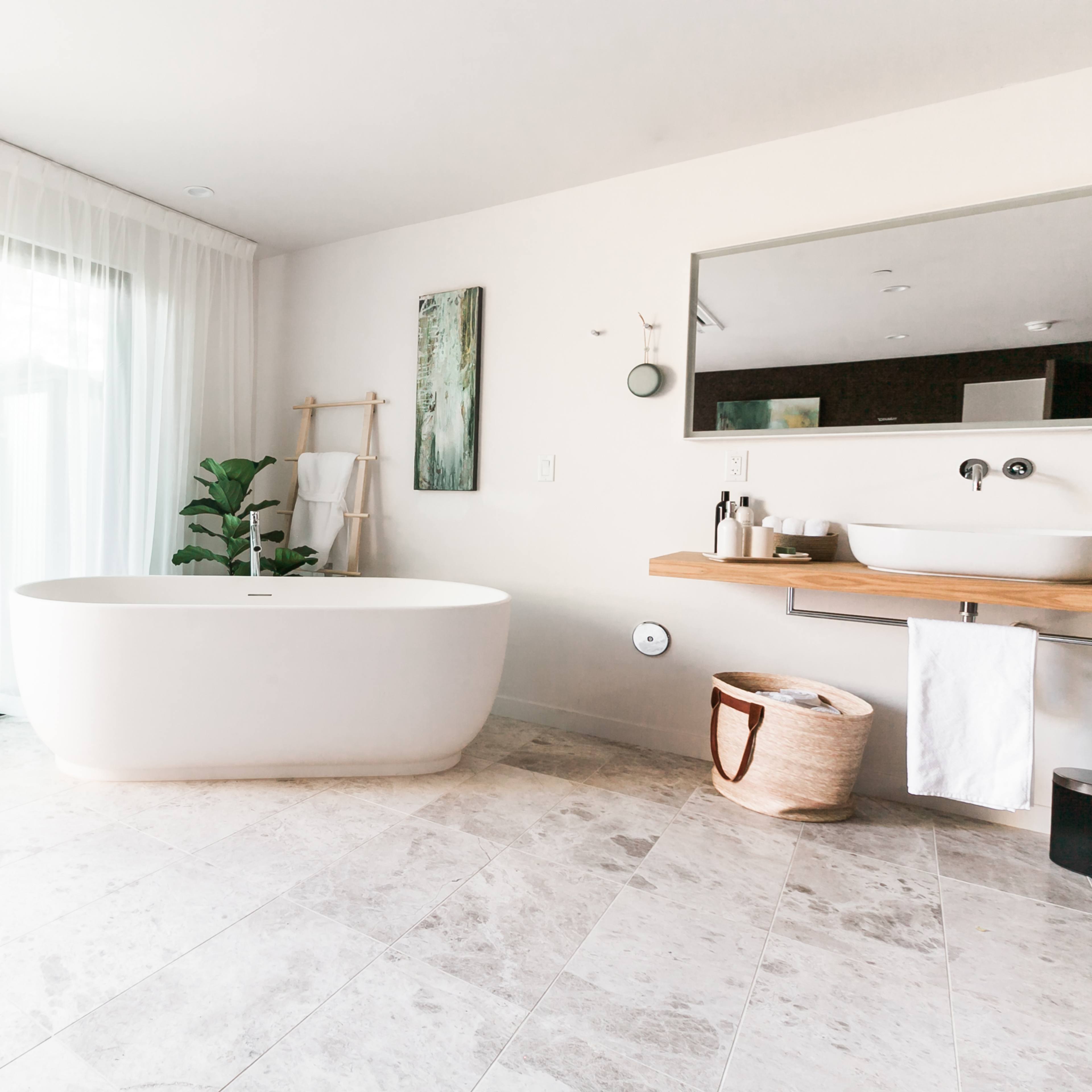 A modern bathroom with a freestanding bathtub, a wooden counter with a sink, and large windows allowing natural light.