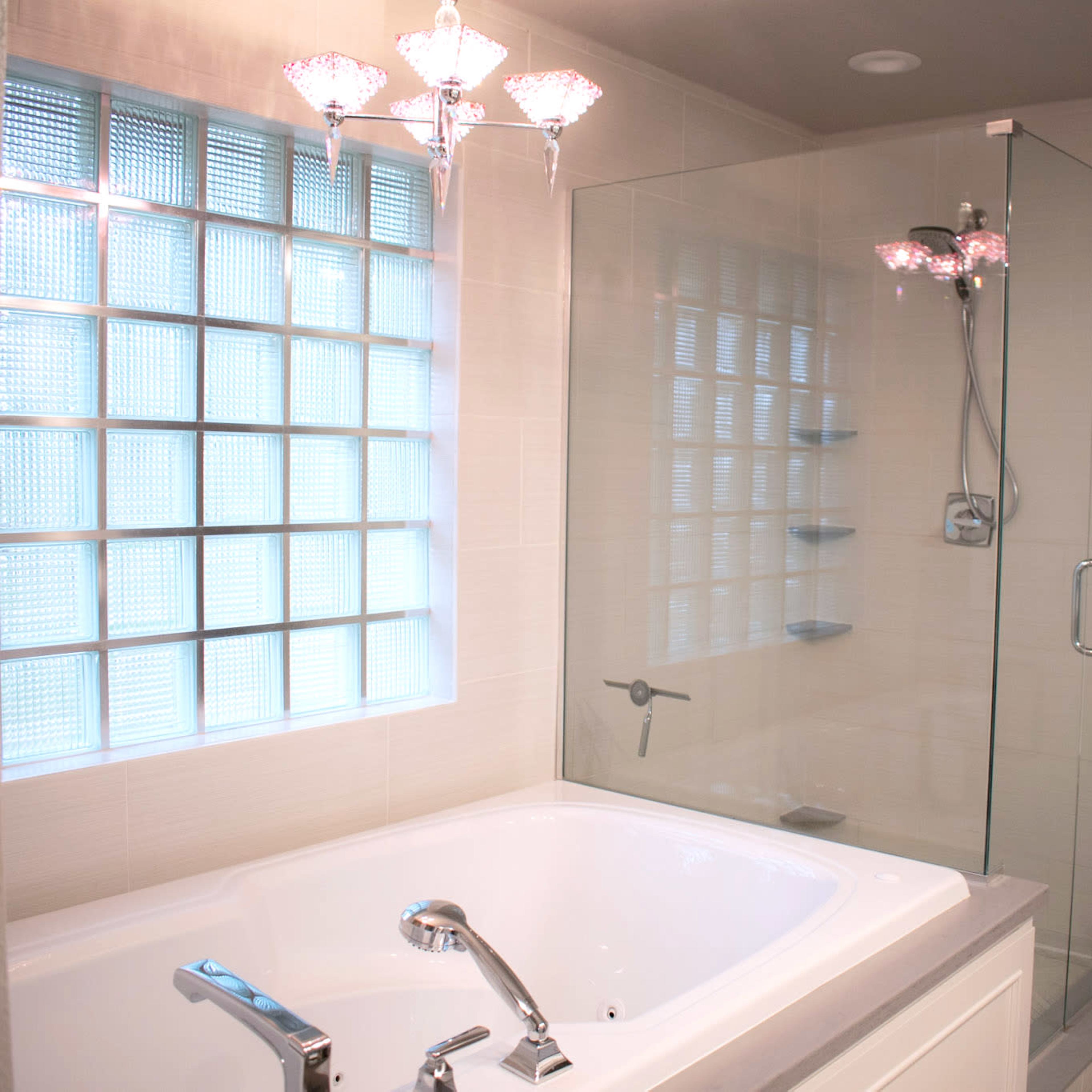 A modern bathroom featuring a glass-enclosed shower, a freestanding bathtub, and a window with glass block panes.