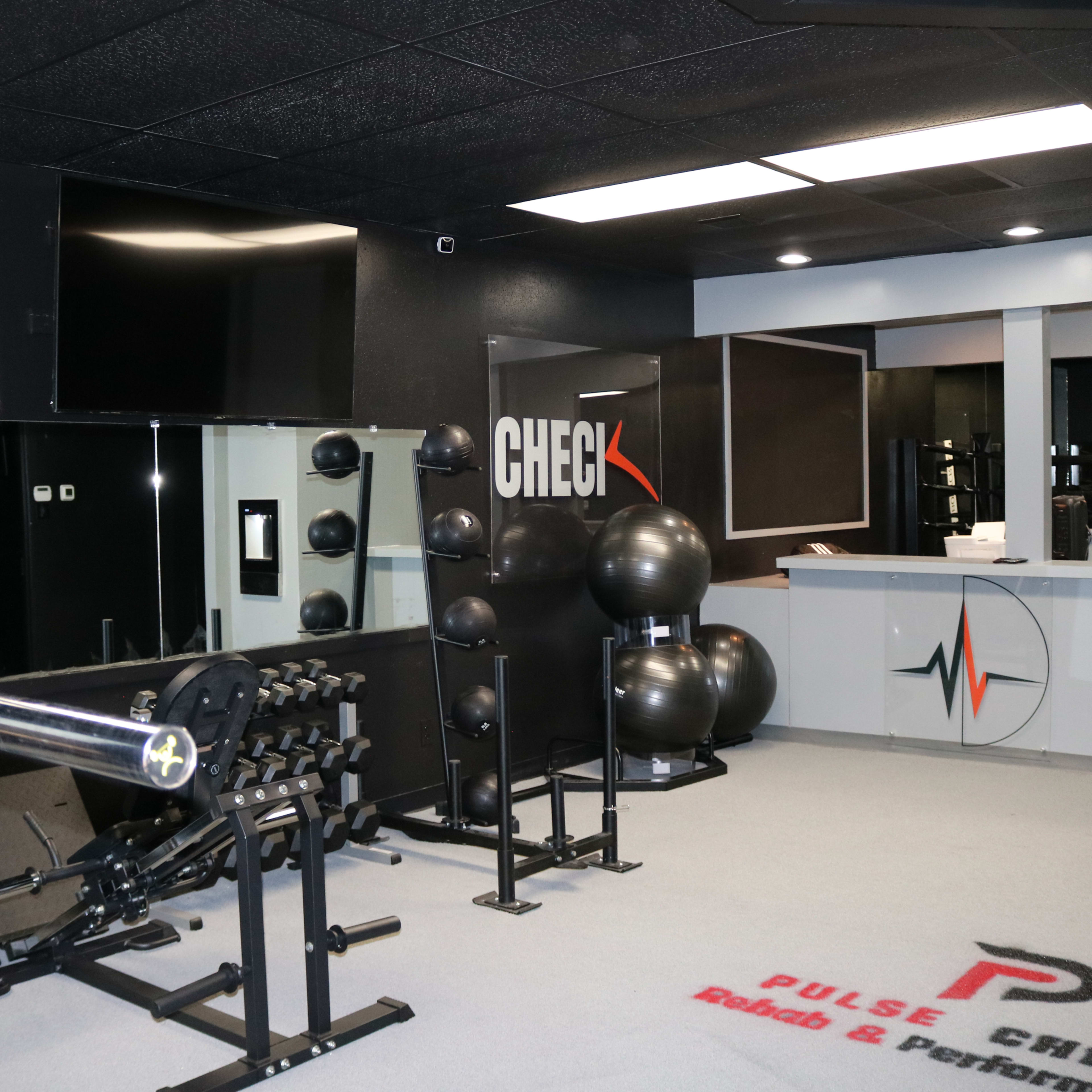 A modern gym interior featuring exercise equipment, free weights, and fitness accessories arranged neatly in a well-lit space.