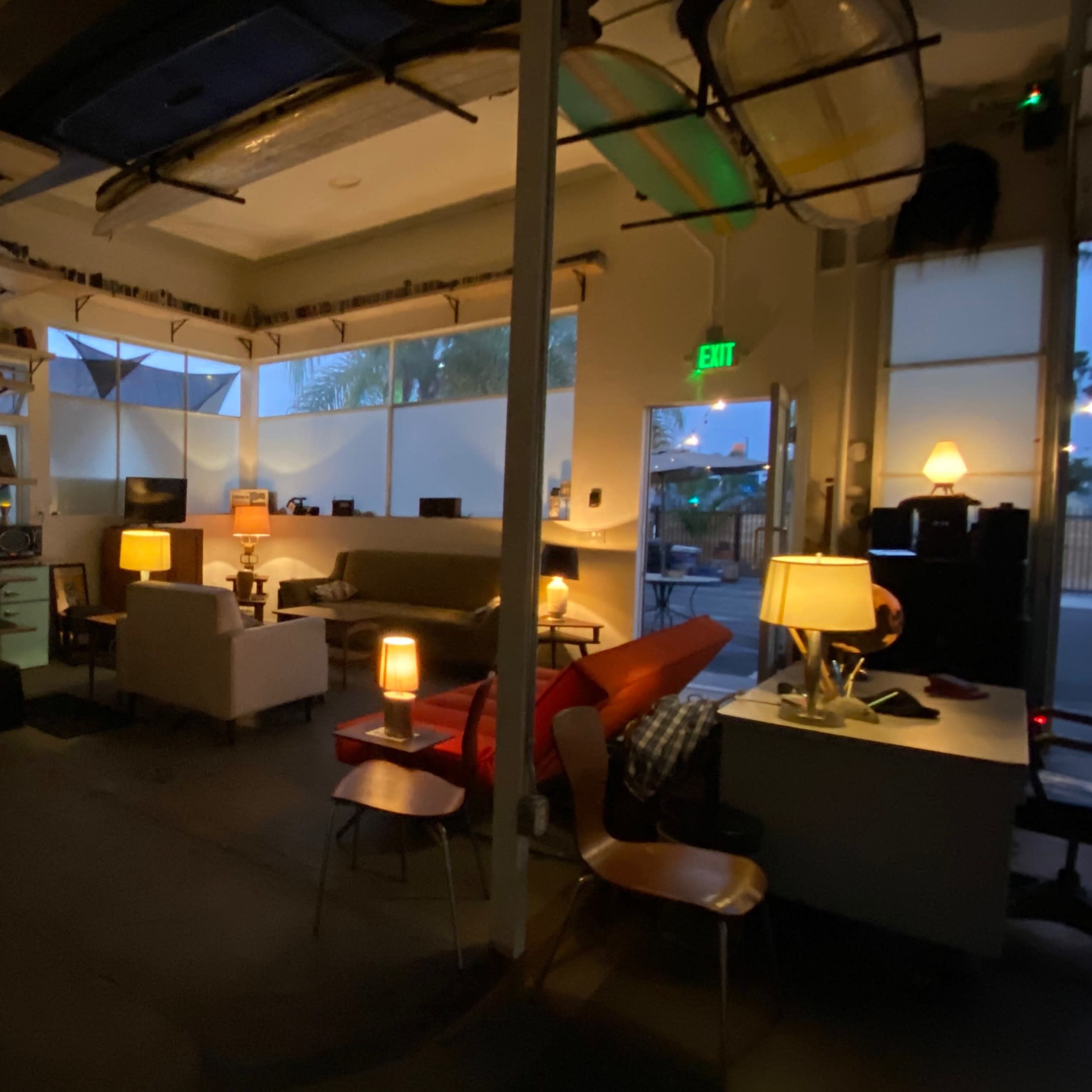 A dimly lit living space with a couch, small table lamps, a desk, and an adjacent bathroom visible through an open door.