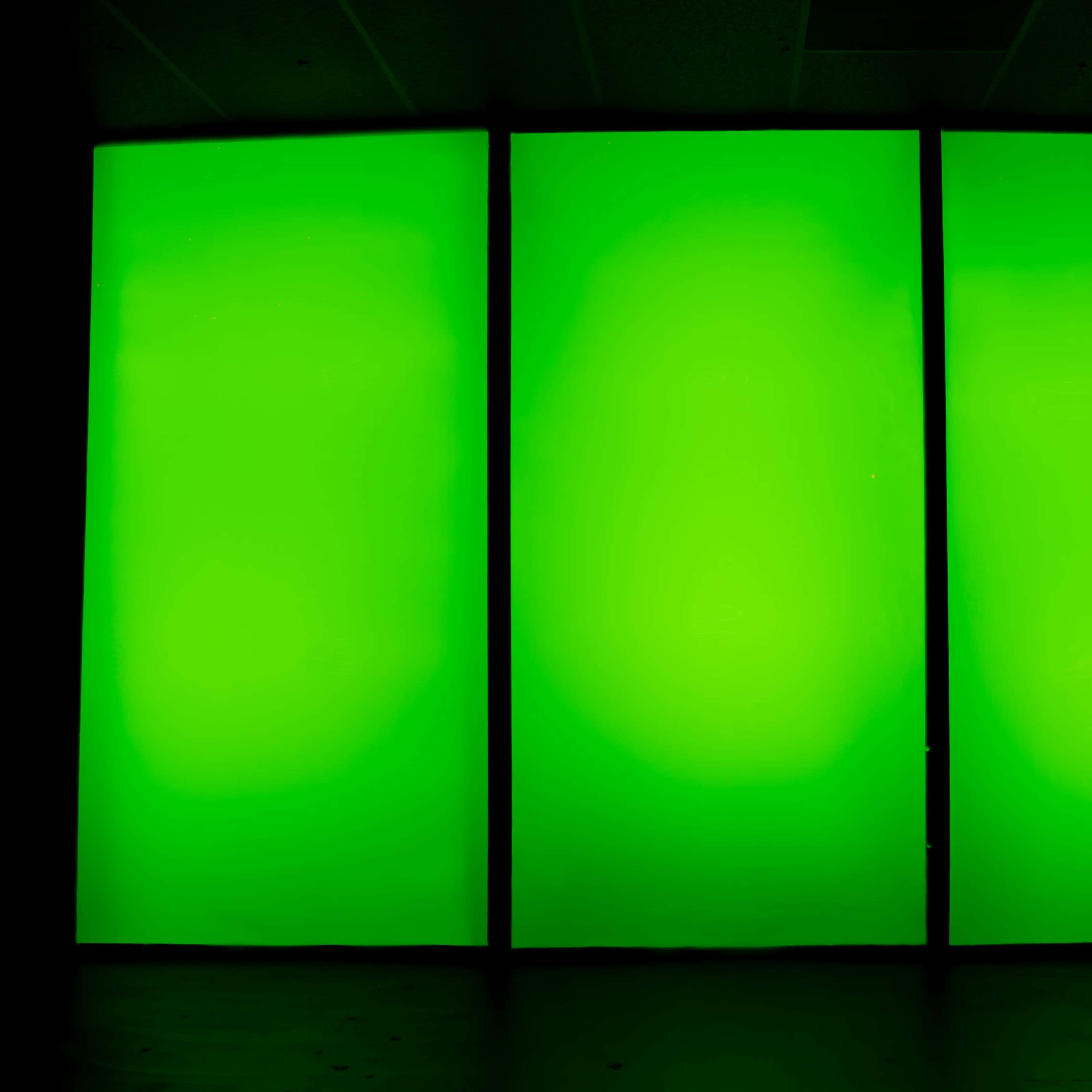 Three large green panels are illuminated and stand against a dark background.