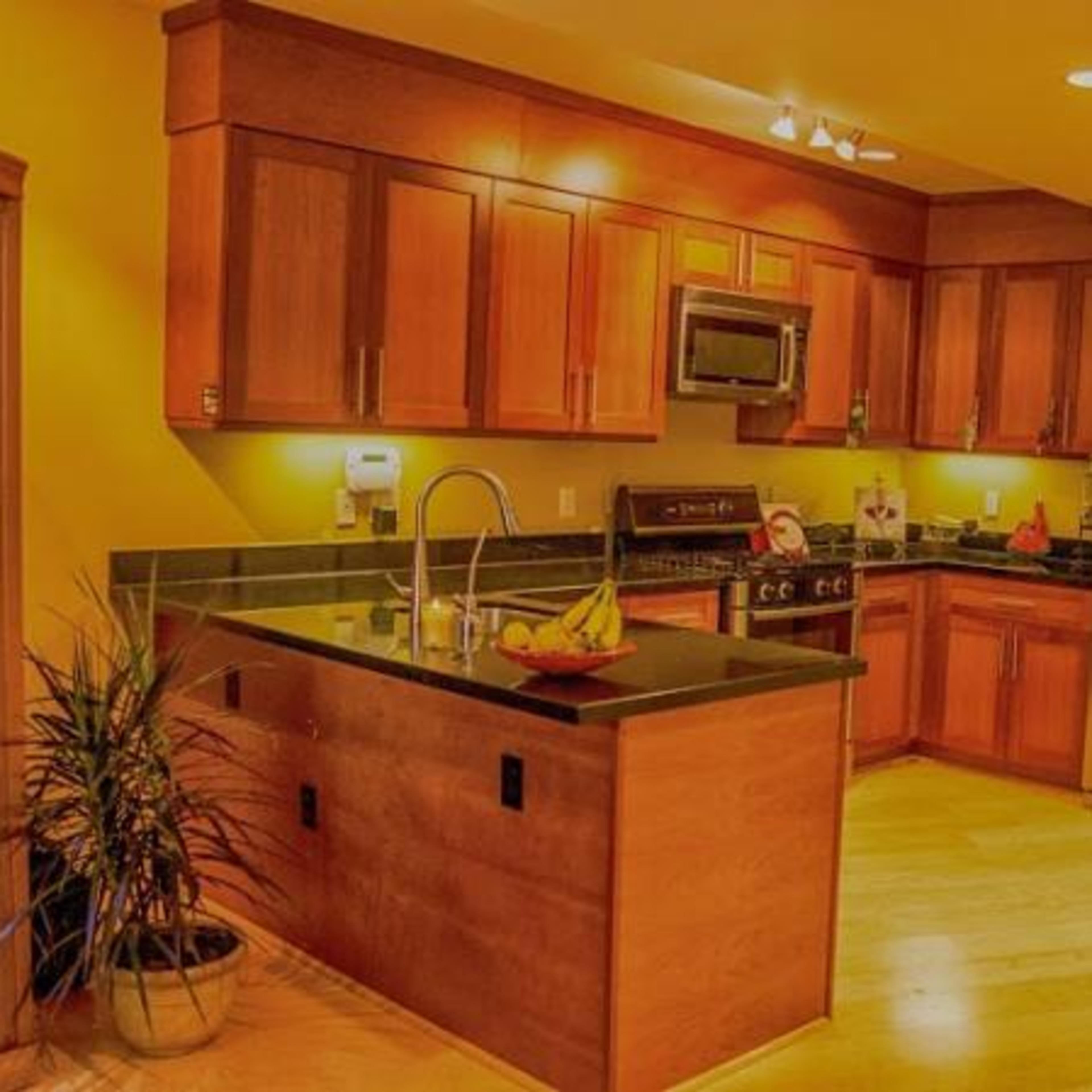 A kitchen featuring wooden cabinets, stainless steel appliances, and a centrally placed island with a bowl of fruit.