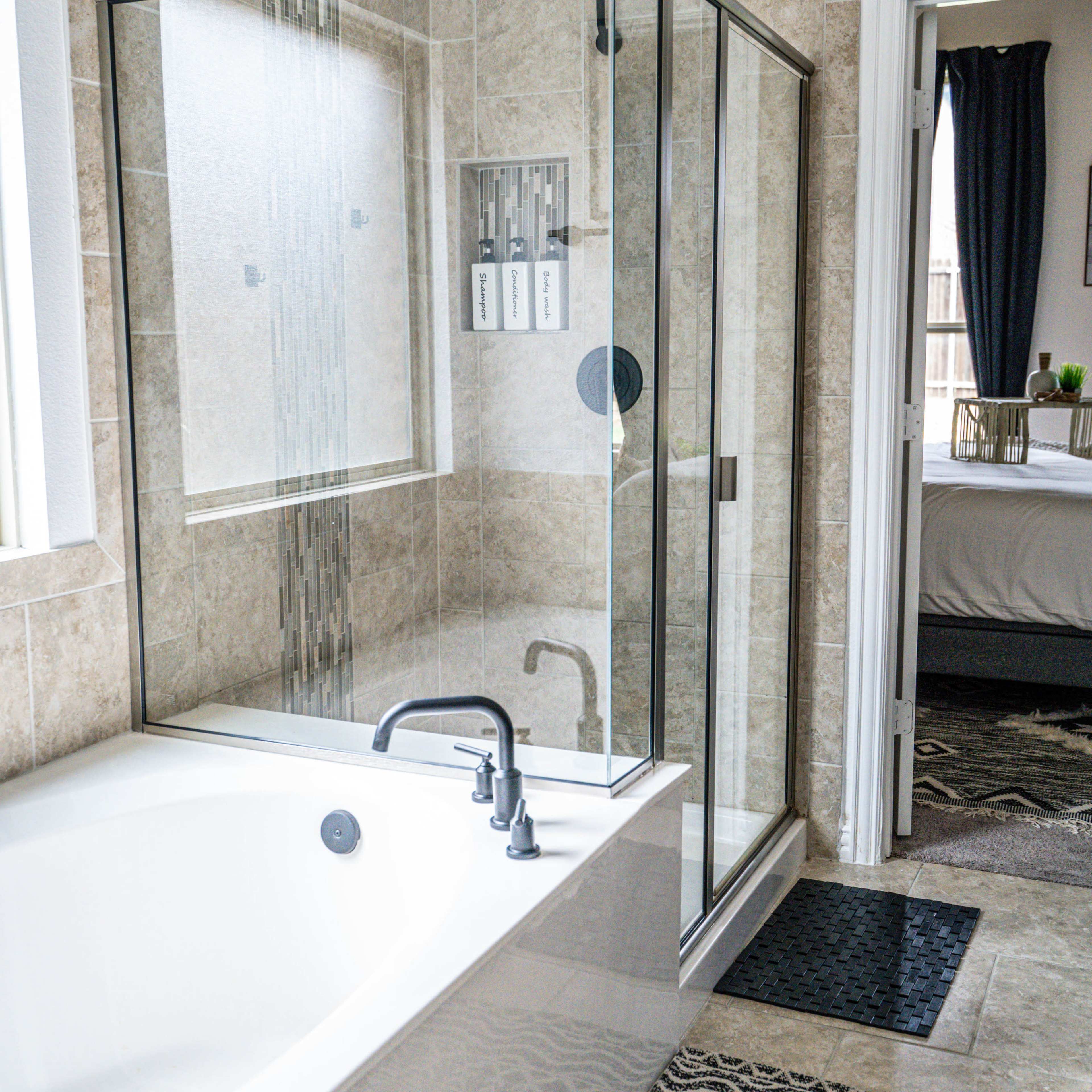 A bathroom featuring a glass-enclosed shower, a freestanding bathtub, and tiled walls.