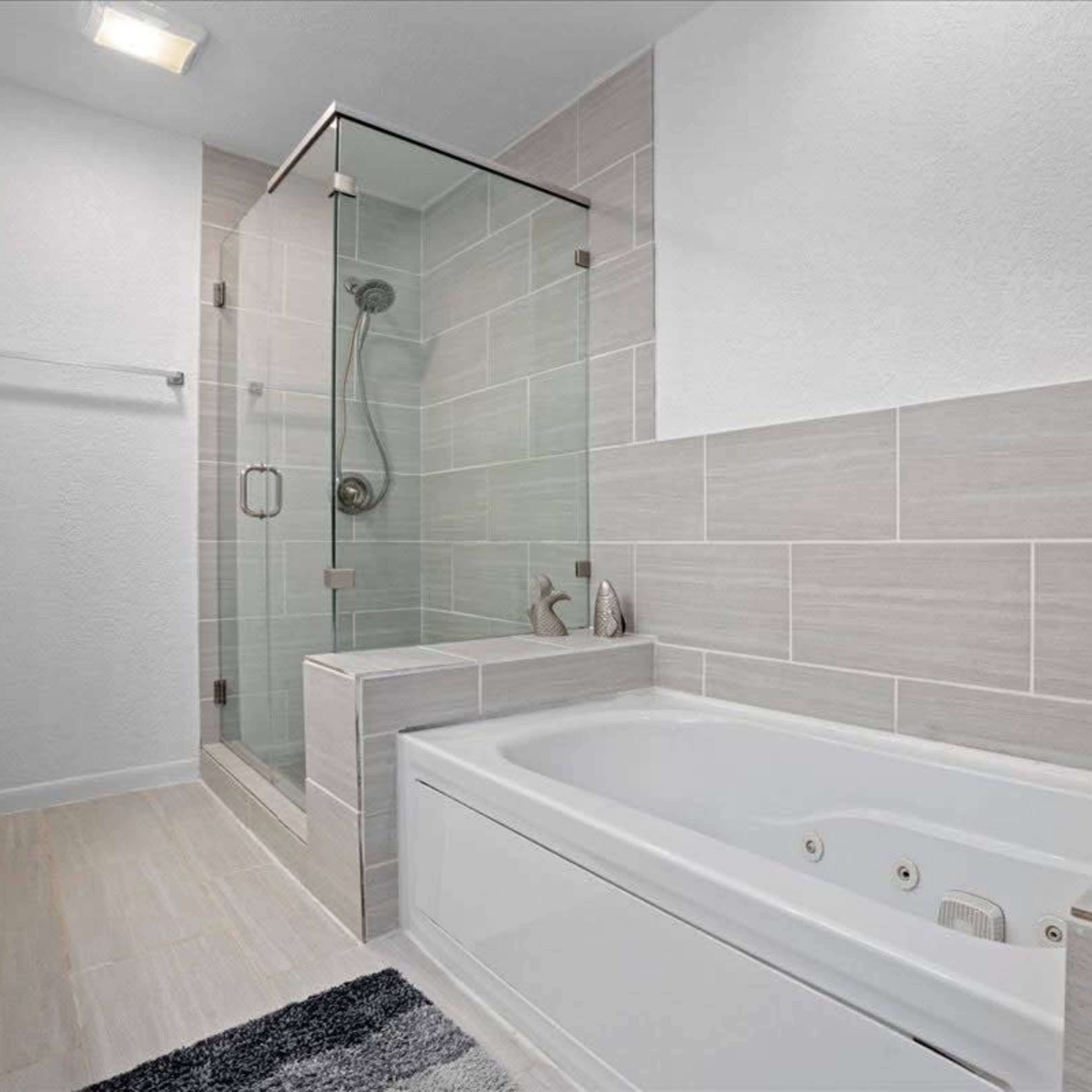 A modern bathroom featuring a glass shower enclosure, a freestanding bathtub, and tiled walls.