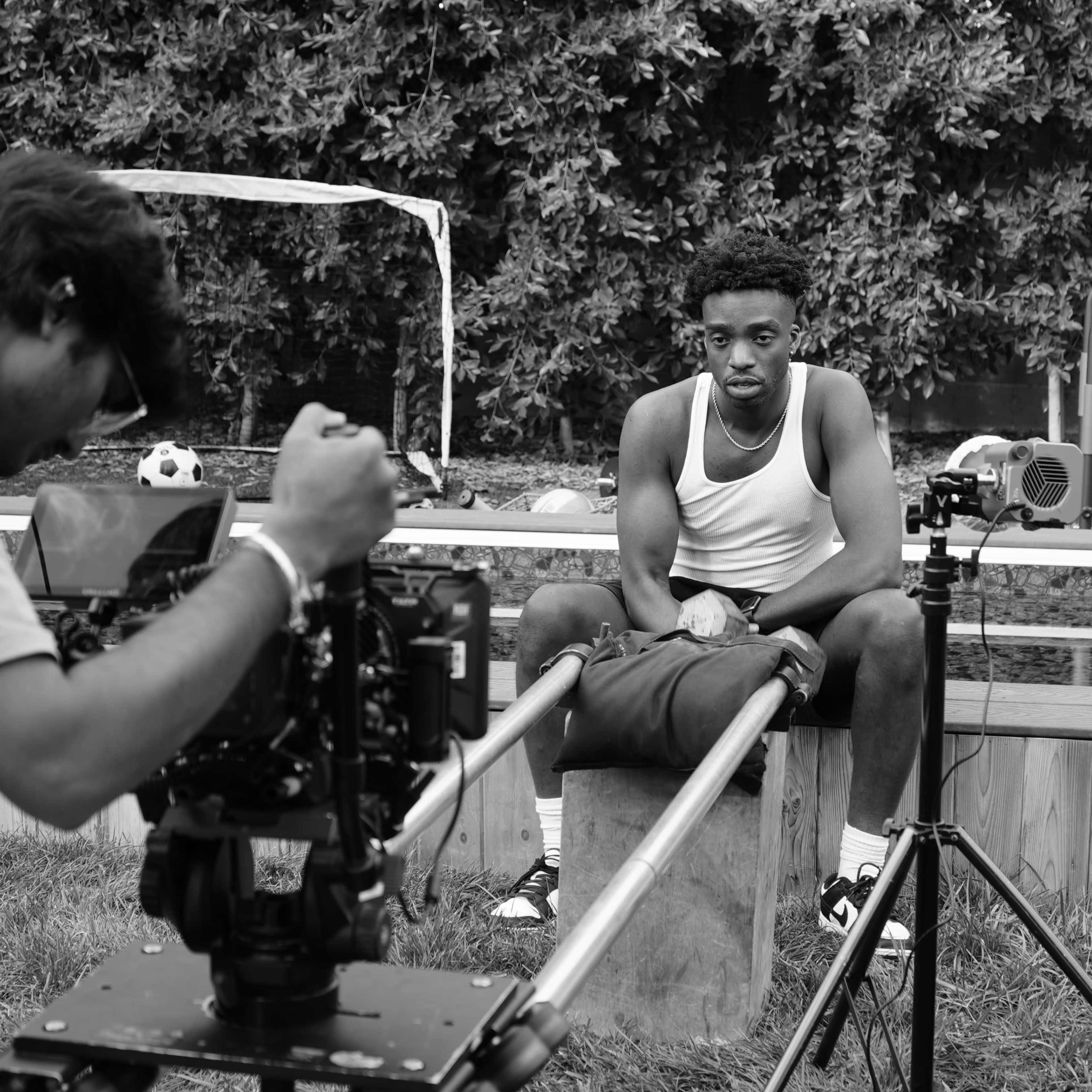 A filmmaker captures a seated subject on a playground set while preparing for a shoot.