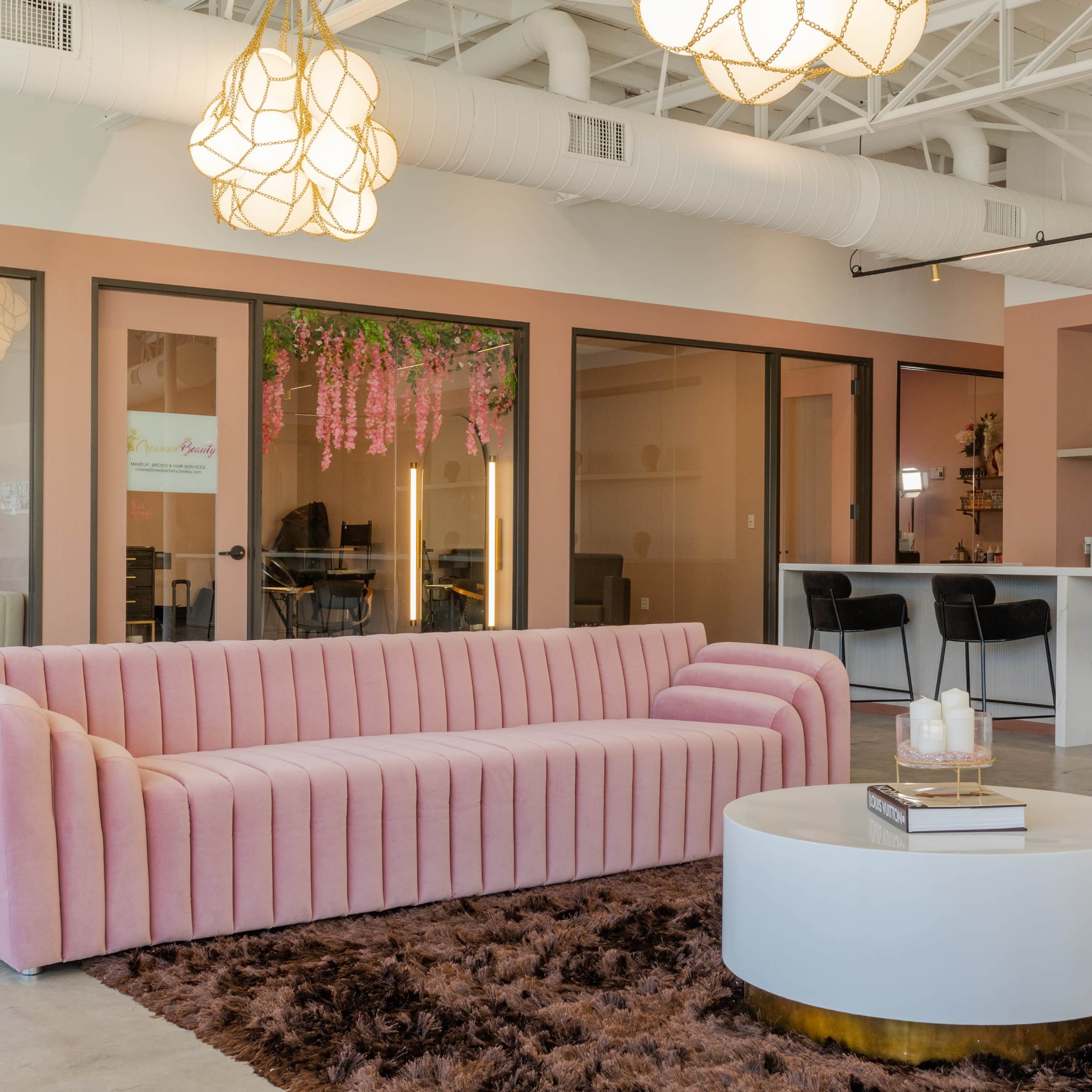 A modern interior space featuring a pink striped sofa, a round white coffee table, and a textured brown area rug under stylish pendant lighting.
