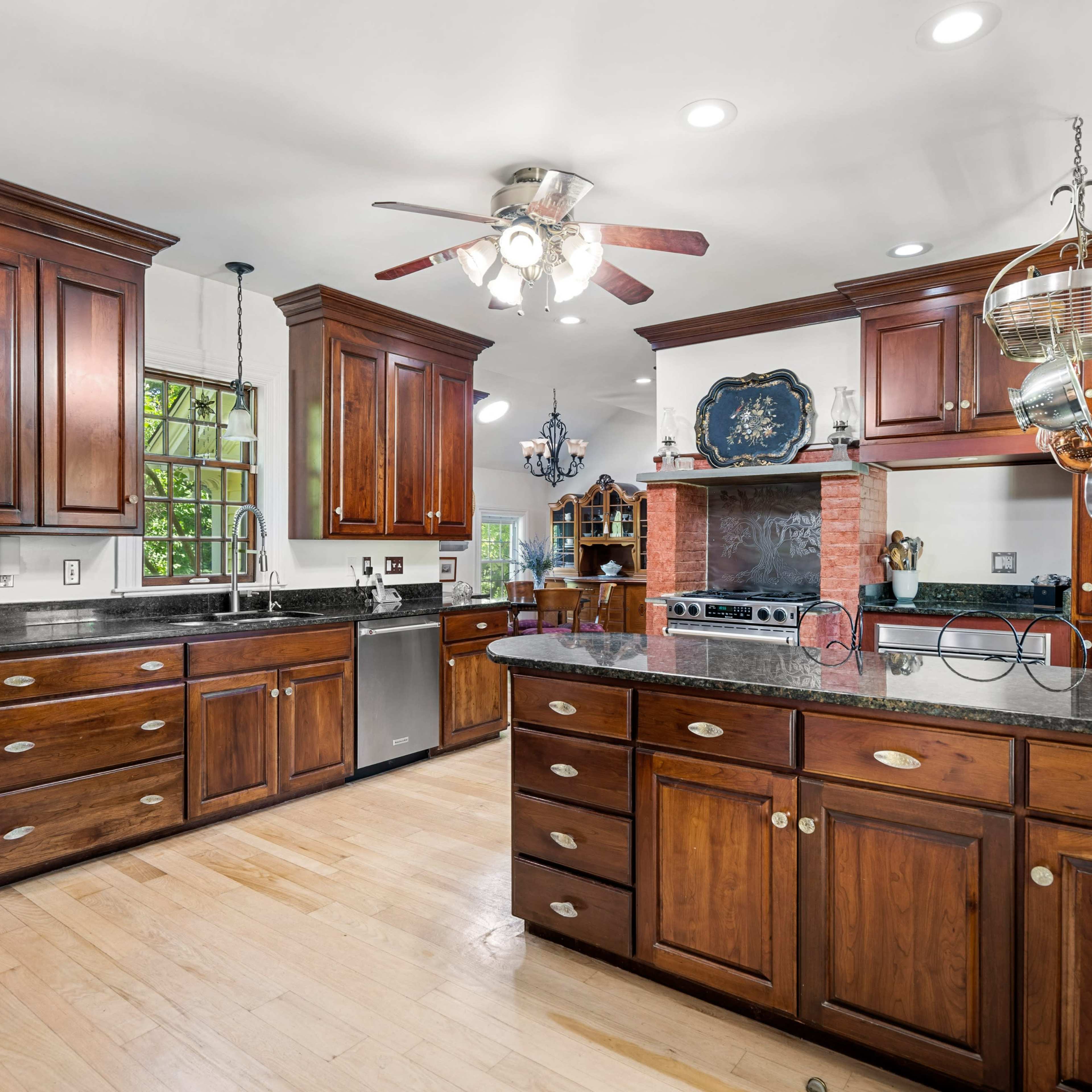 A kitchen with dark wood cabinetry, stainless steel appliances, and a central island with a black countertop.