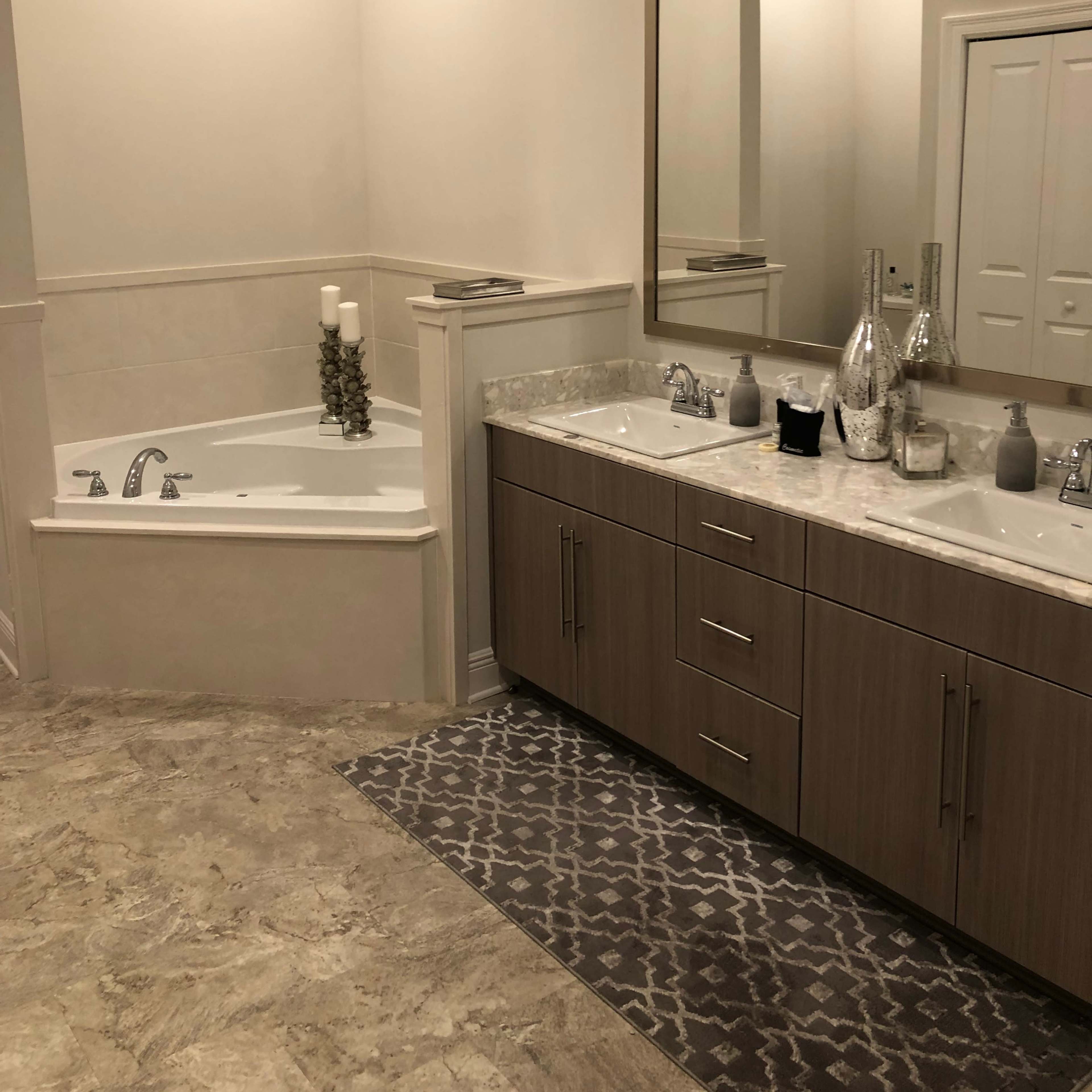 A modern bathroom featuring a freestanding bathtub, a double sink vanity with a marble countertop, and a large mirror above the sinks.