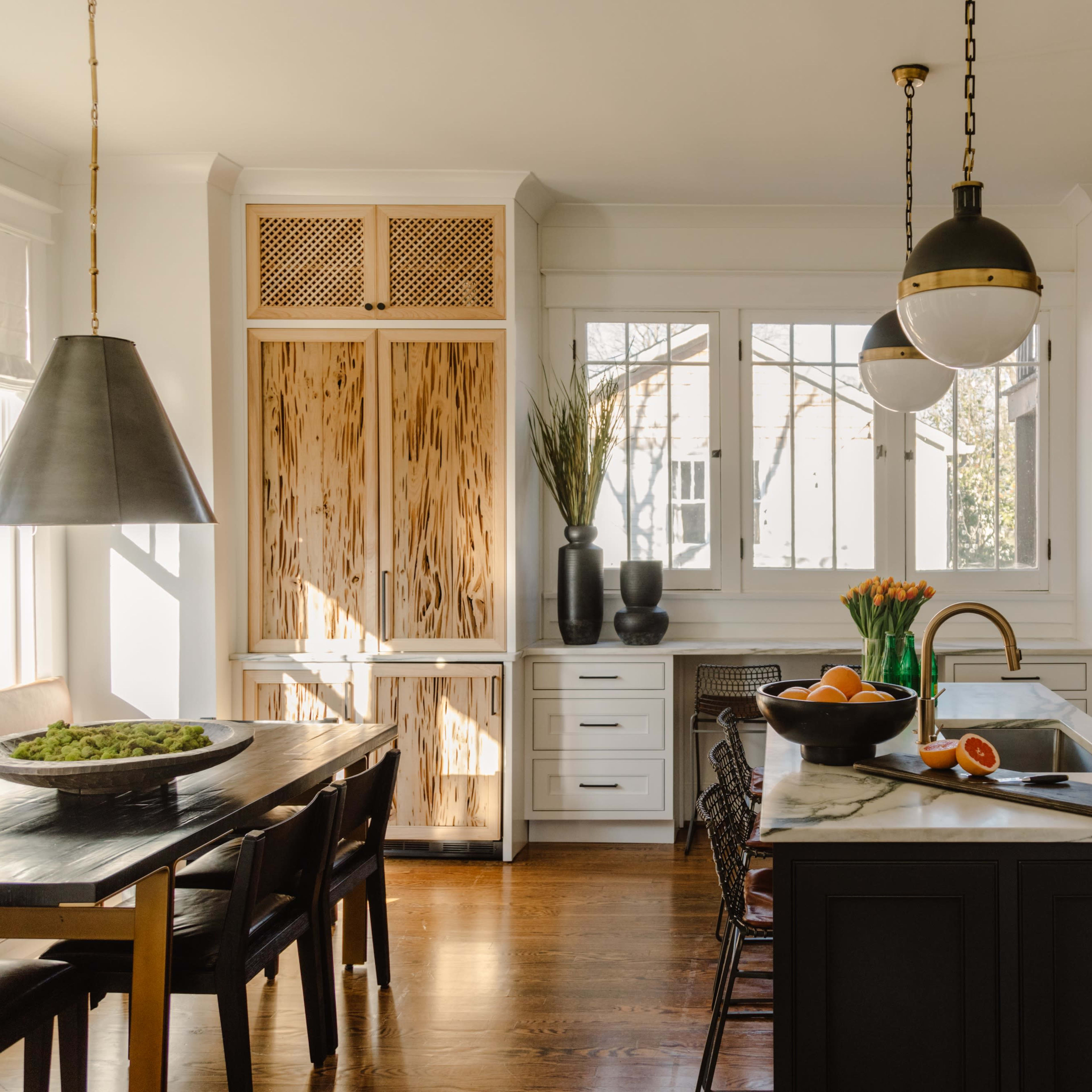 The kitchen features a central island with a marble countertop, wooden cabinets, and a dining table with black chairs.