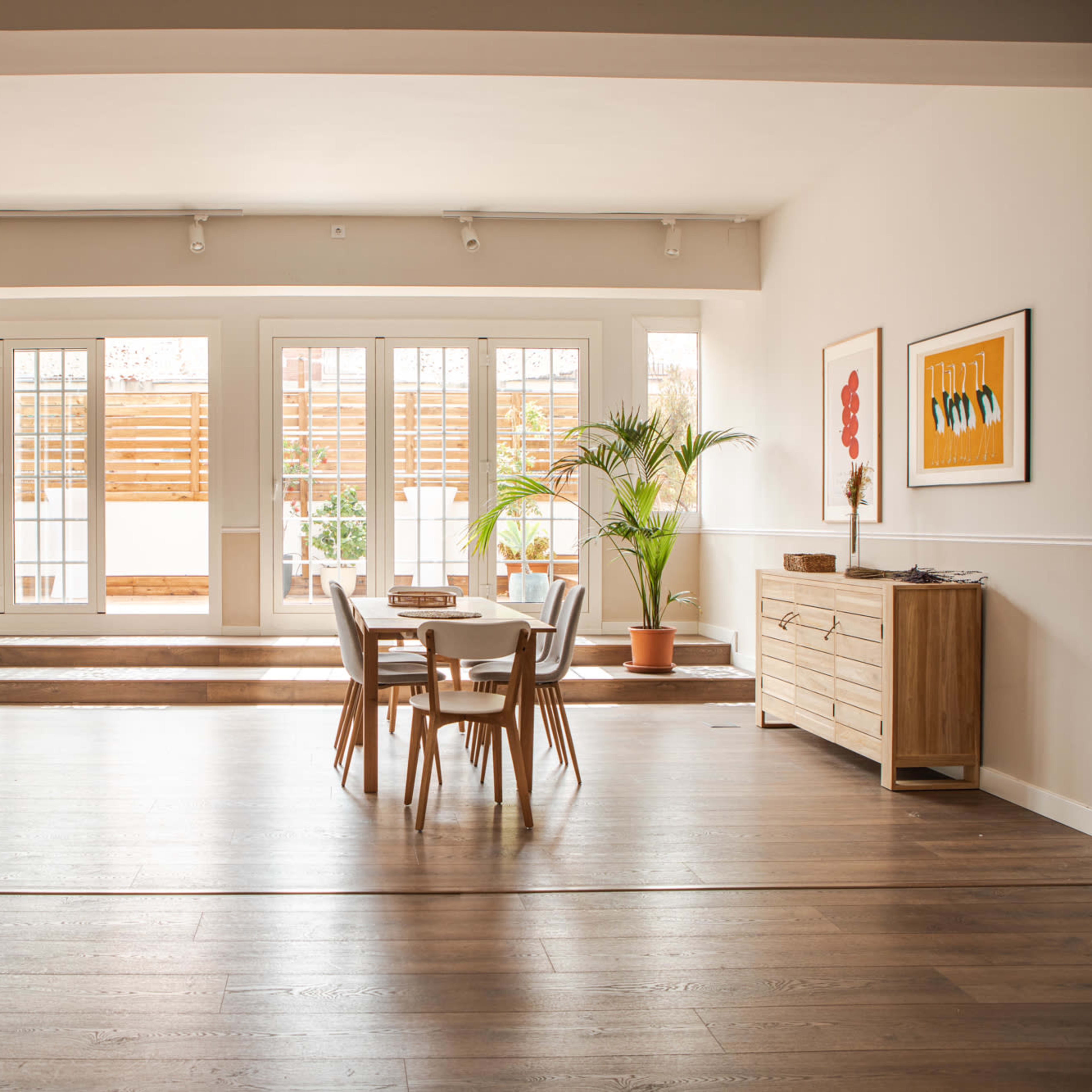 A spacious, well-lit open-concept kitchen and dining area features a wooden table, chairs, and large sliding doors leading to an outdoor space.