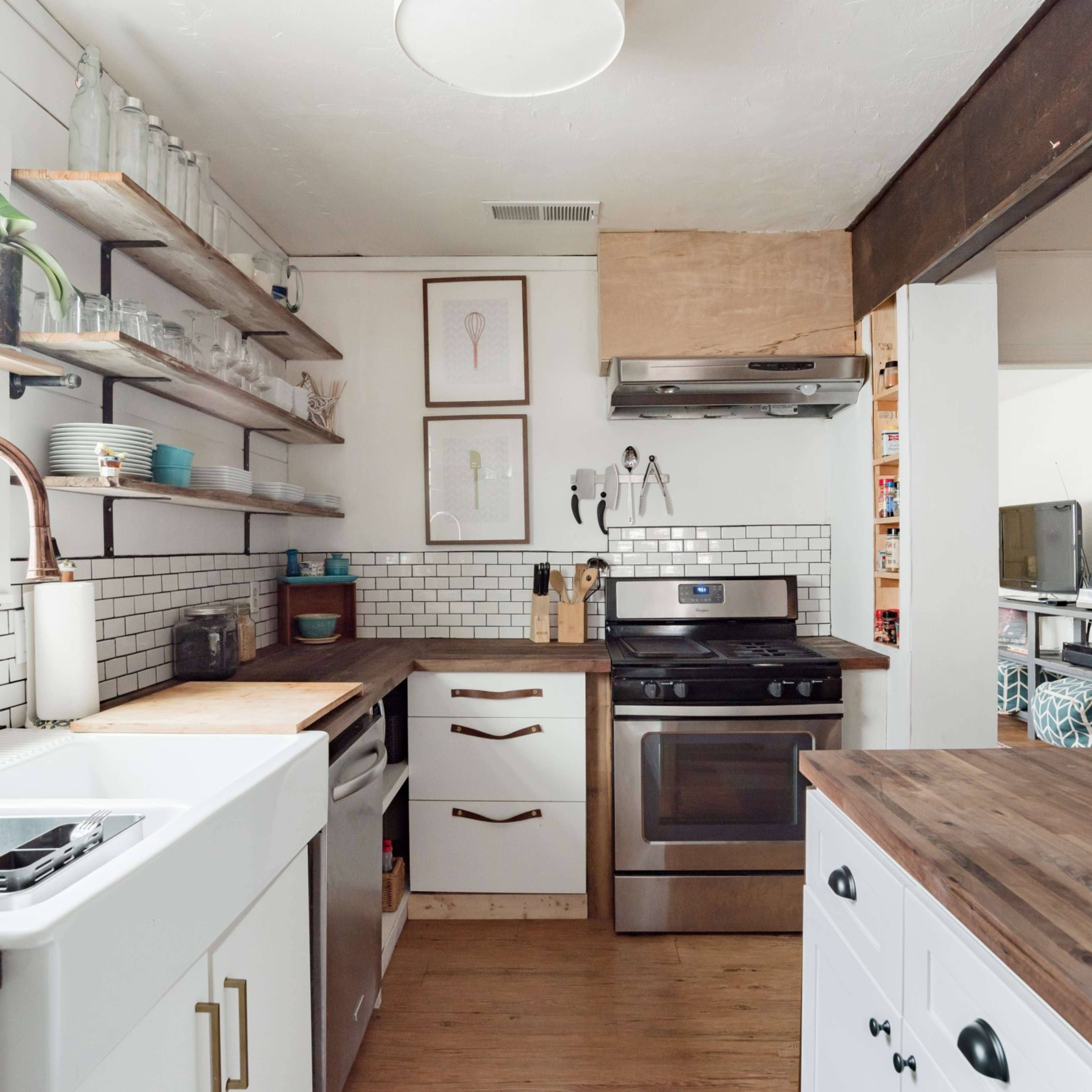 A modern kitchen with open shelving, a stainless steel stove, and a wooden countertop.