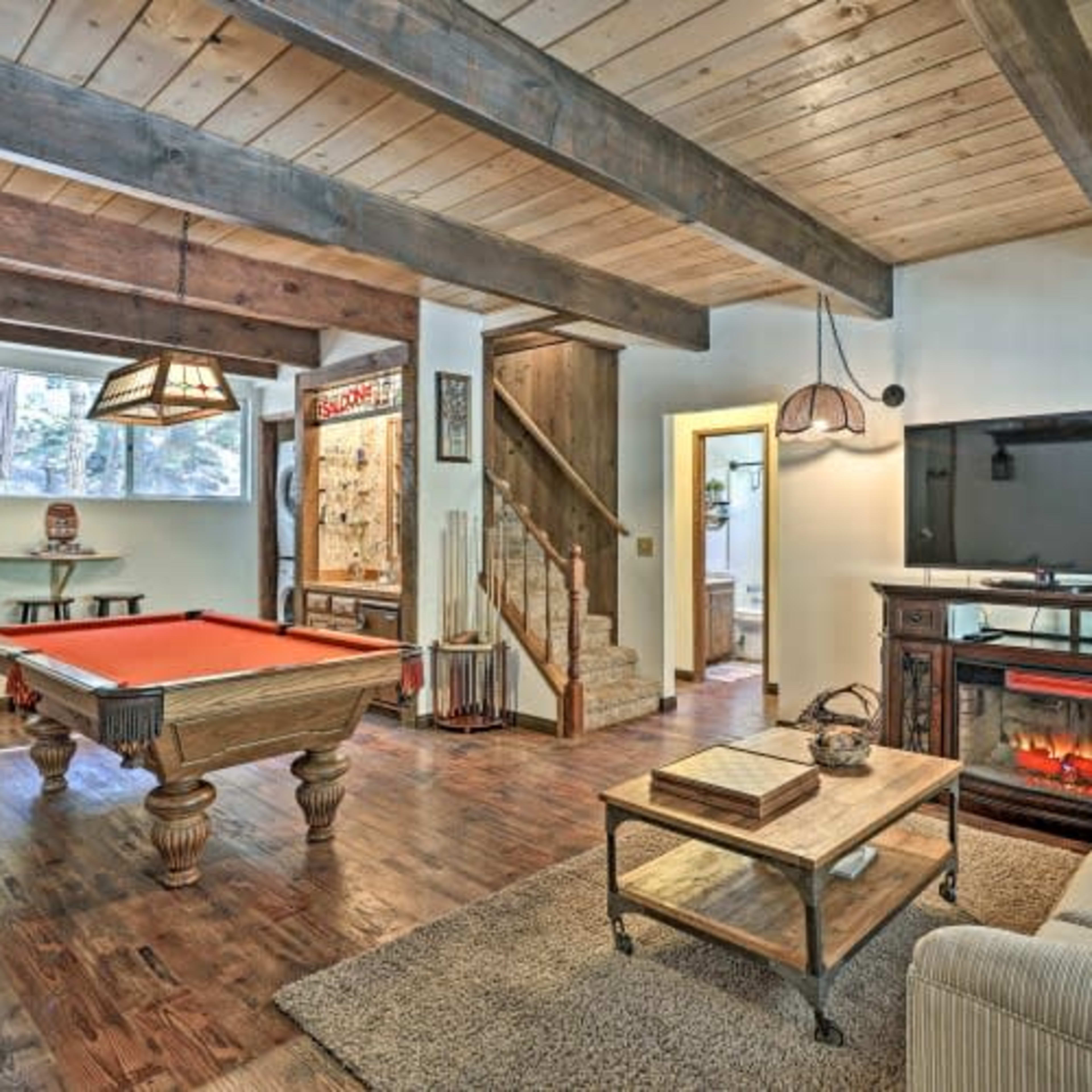 A cozy game room with a pool table, a TV mounted on the wall, a fireplace, and a comfortable seating area.