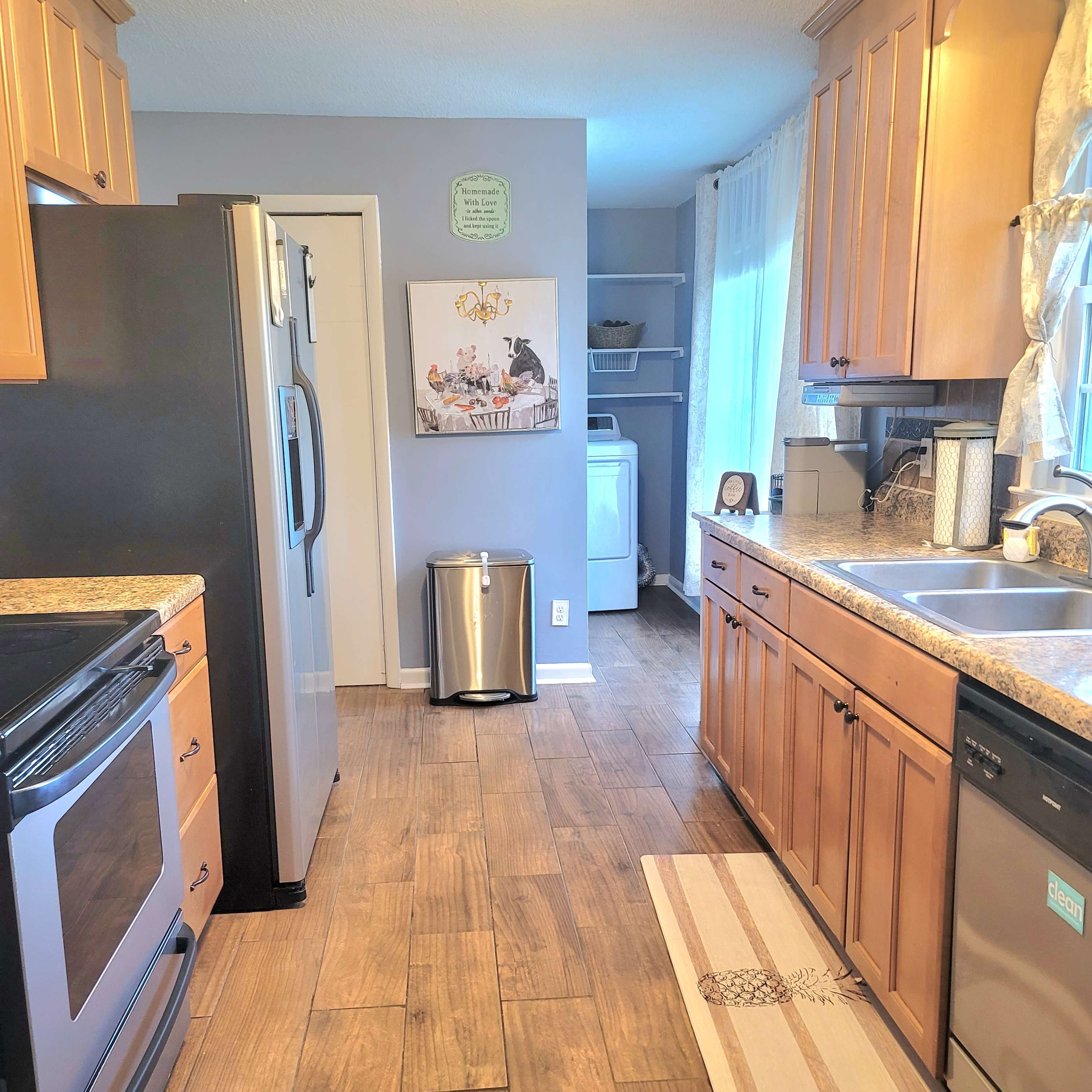 A modern kitchen with wooden cabinets, stainless steel appliances, and a tiled floor, featuring a view of a clean, organized space.
