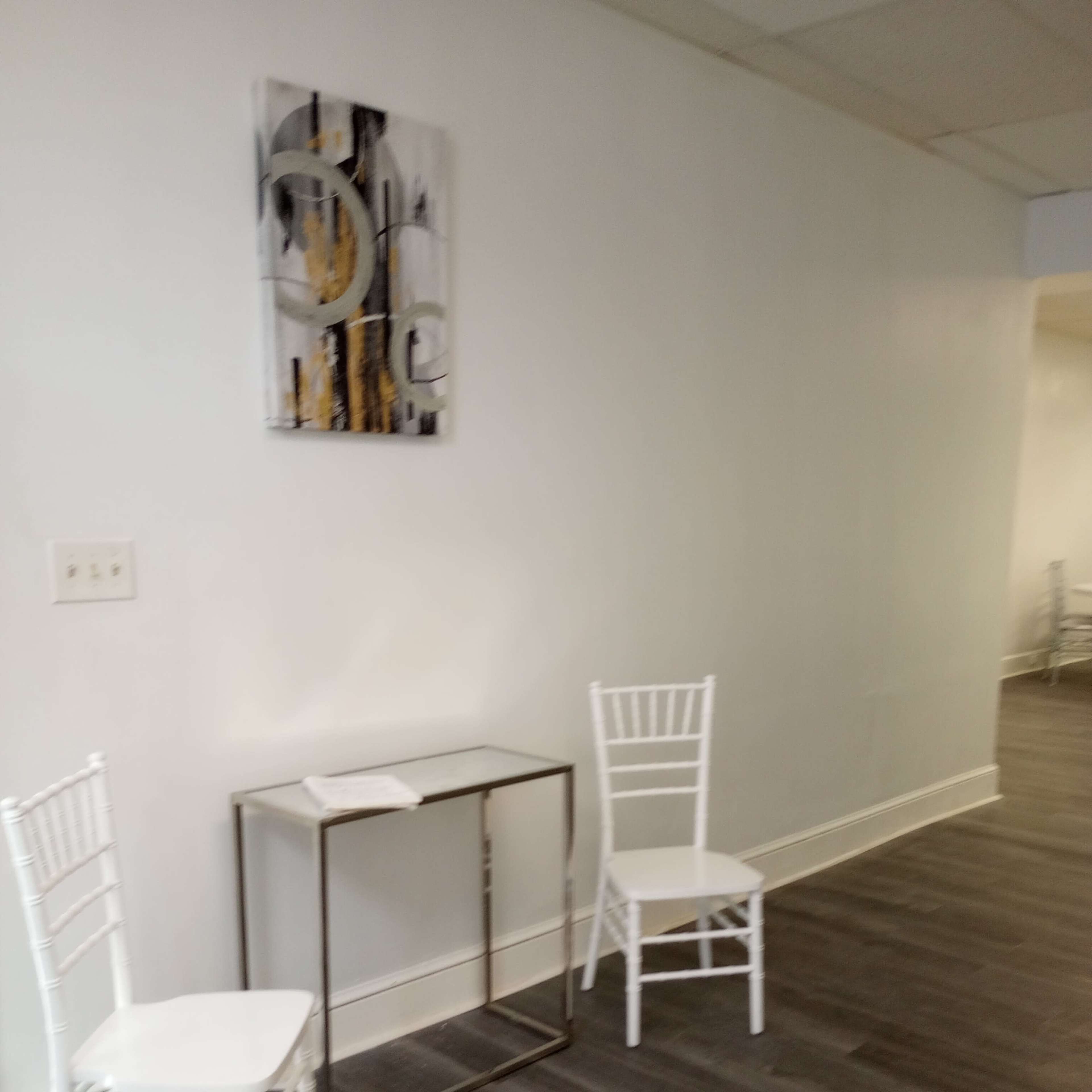 A minimalistic interior space with two white chairs and a small table against a light-colored wall.