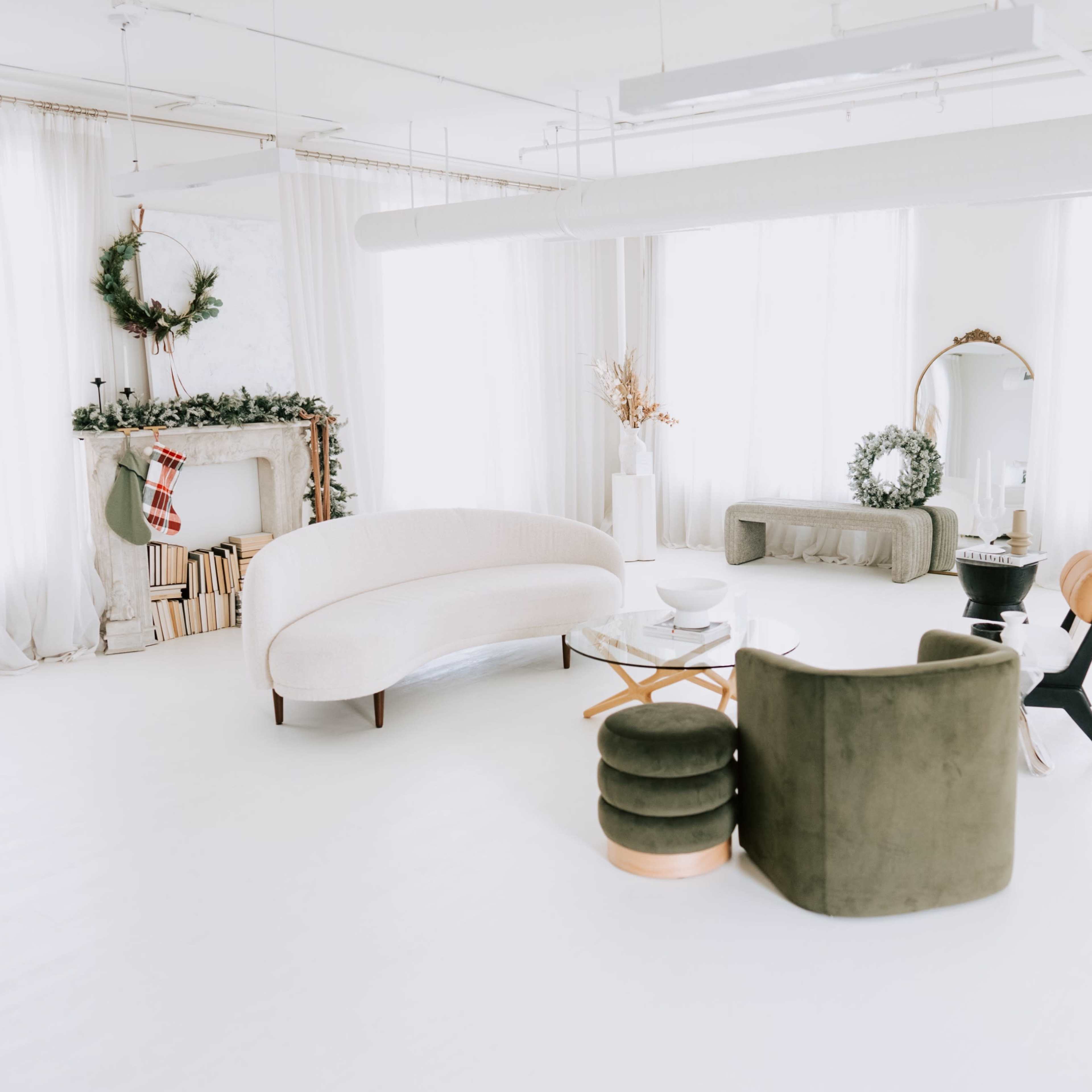 A spacious, well-lit room features a Christmas tree, modern furniture, and holiday decorations.