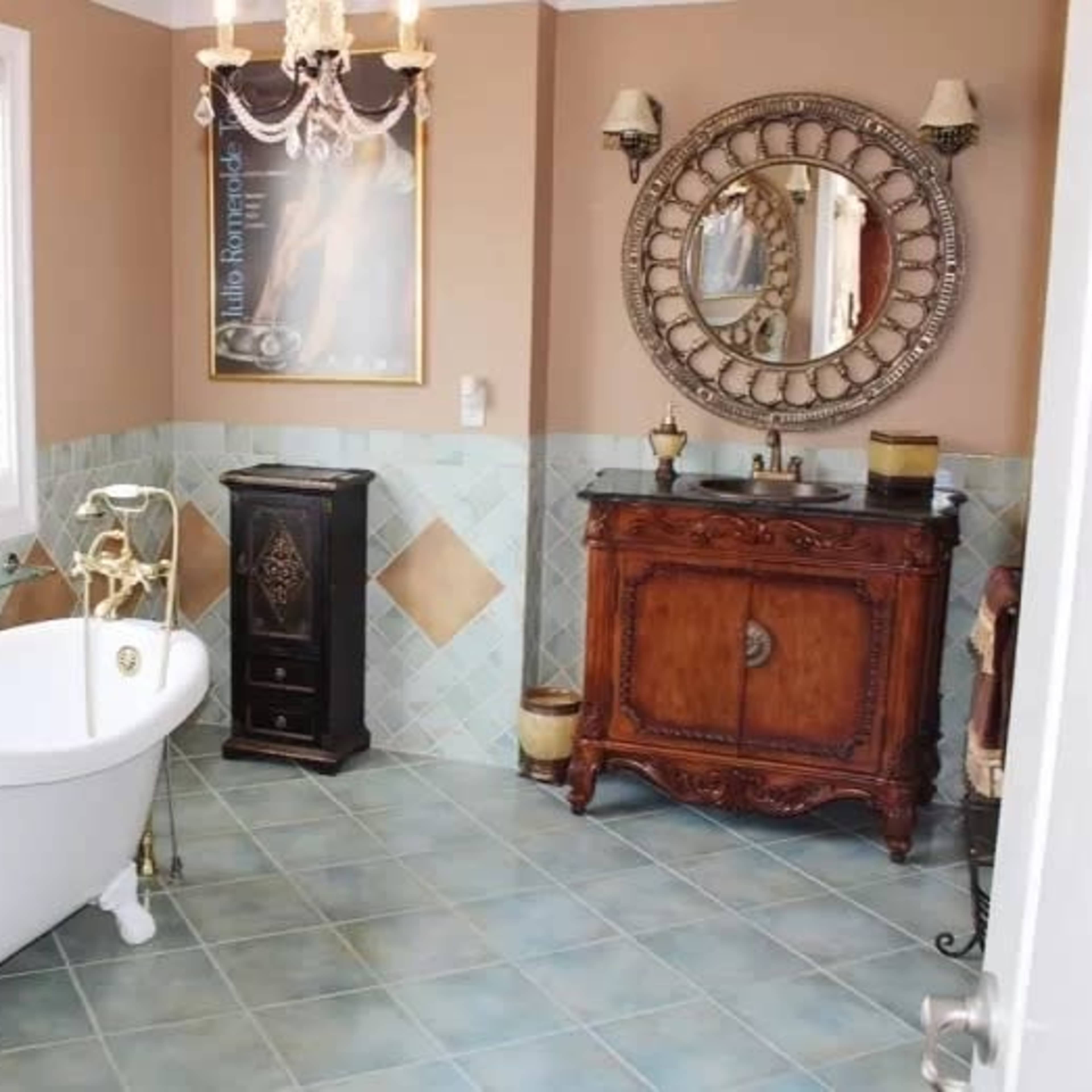 A bathroom featuring a freestanding white bathtub, a vintage-style wooden vanity, and decorative tiled walls.