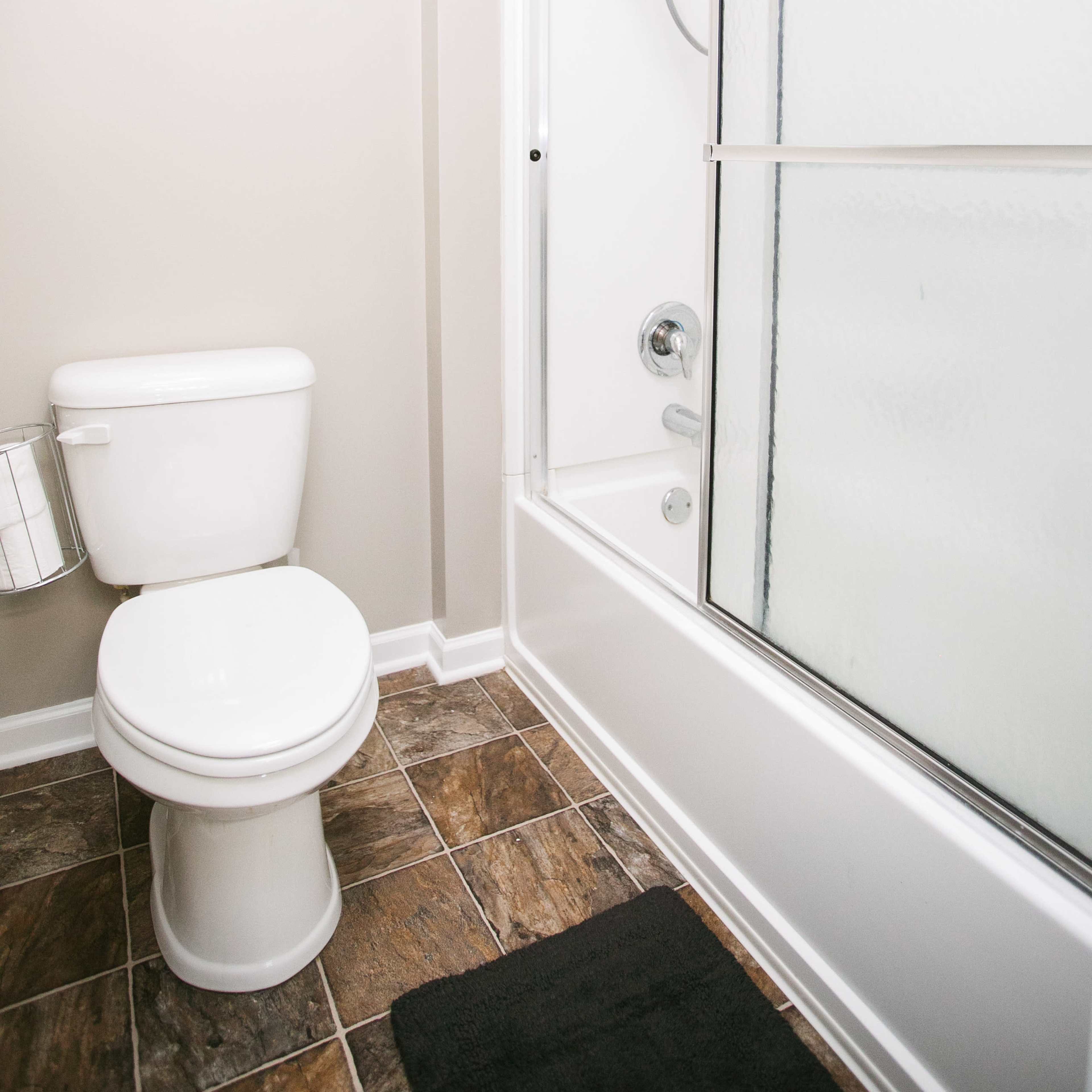 A bathroom with a toilet, a shower with a glass door, and a tiled floor.