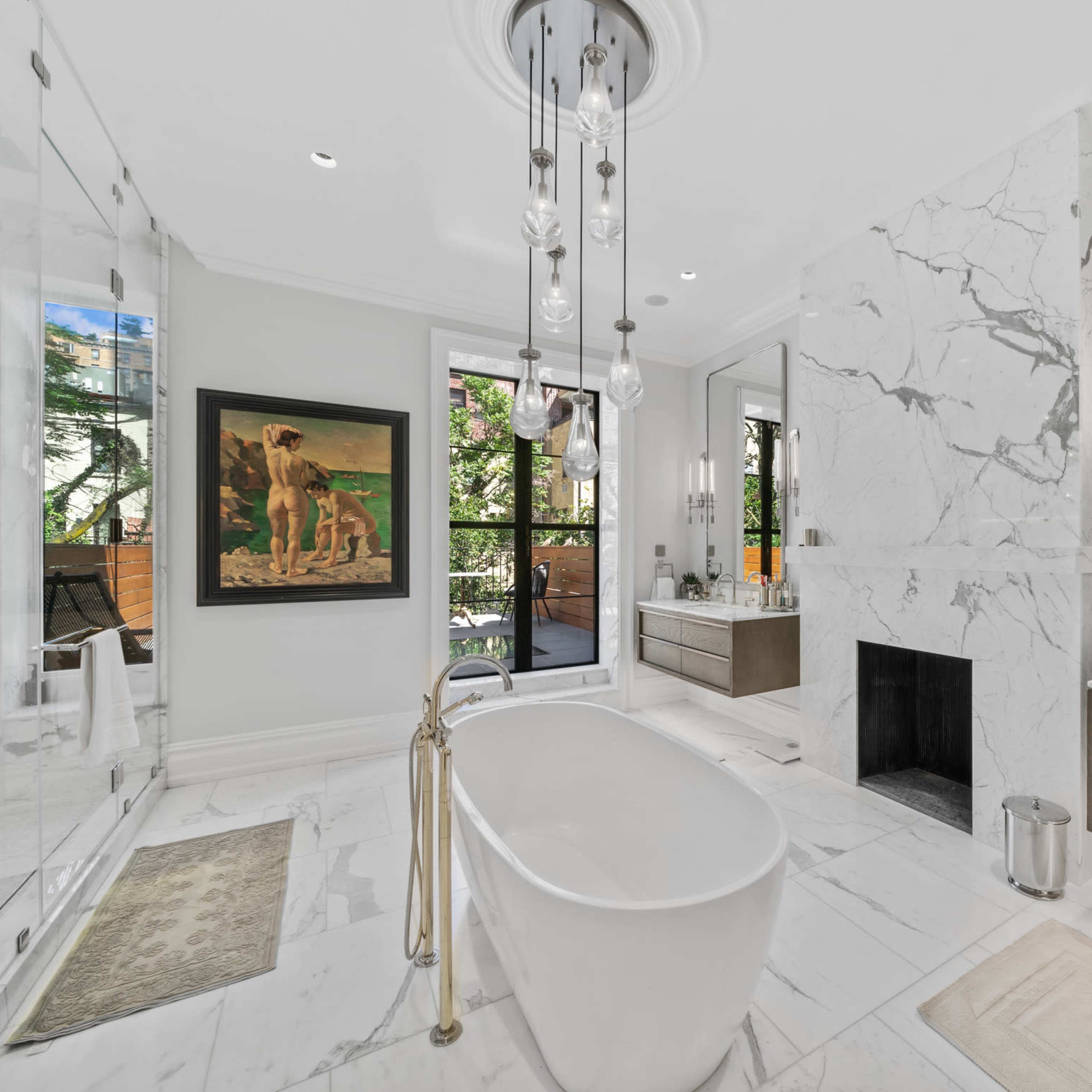 A modern bathroom featuring a freestanding bathtub, a glass shower, a large mirror, and marble tile flooring.