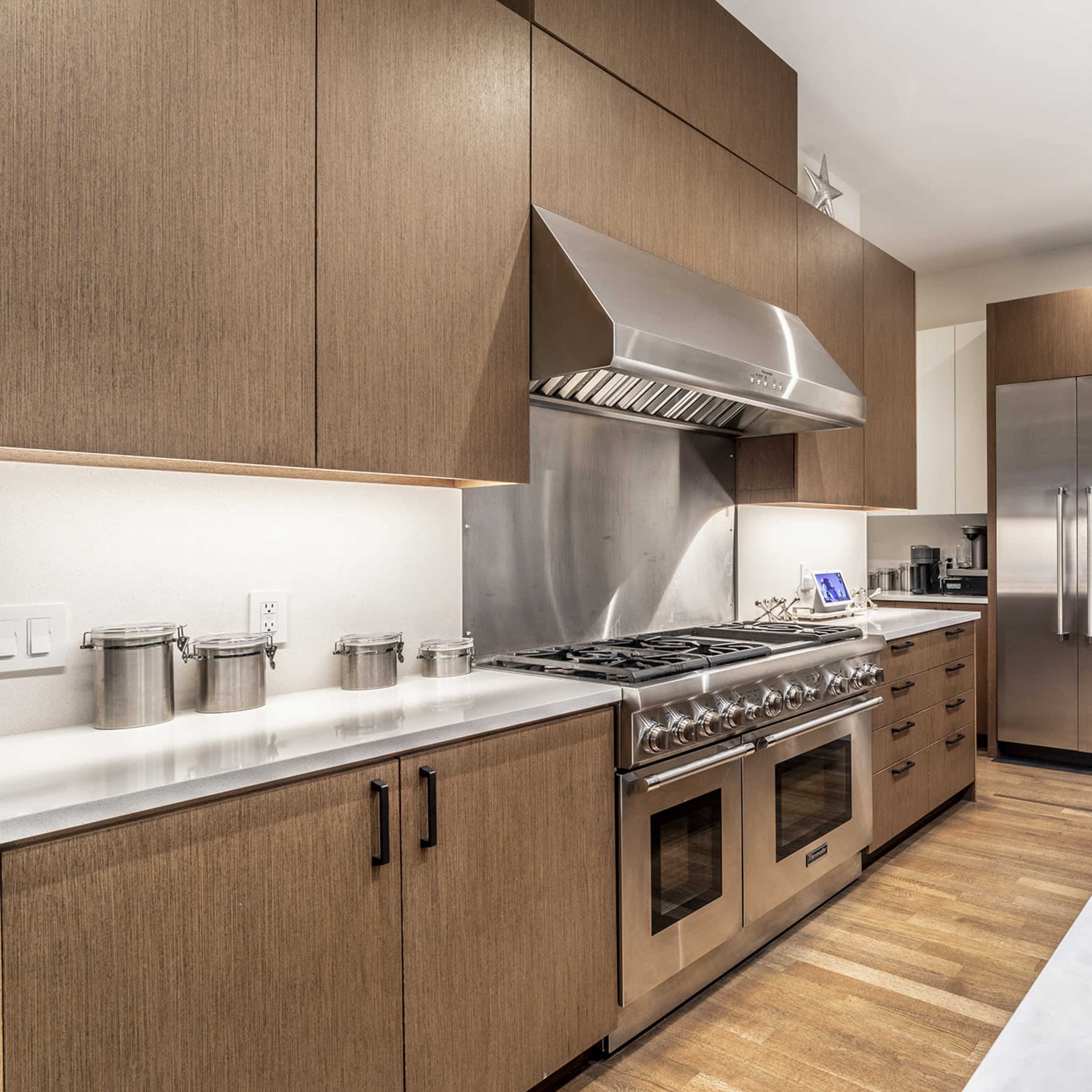A modern kitchen with wooden cabinets, stainless steel appliances, and a marble countertop.
