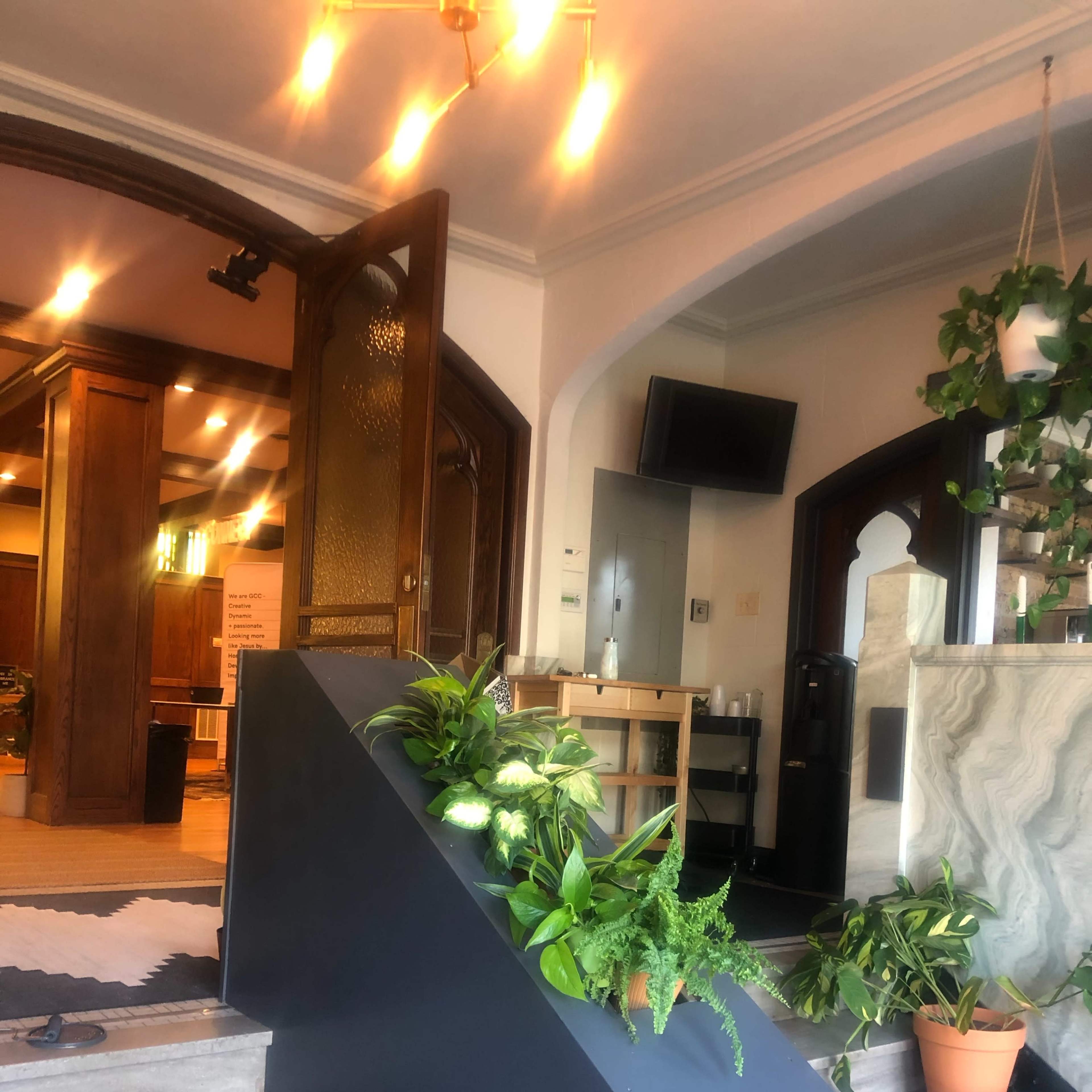 An indoor staircase with plants arranged along the side, leading to a well-lit reception area.