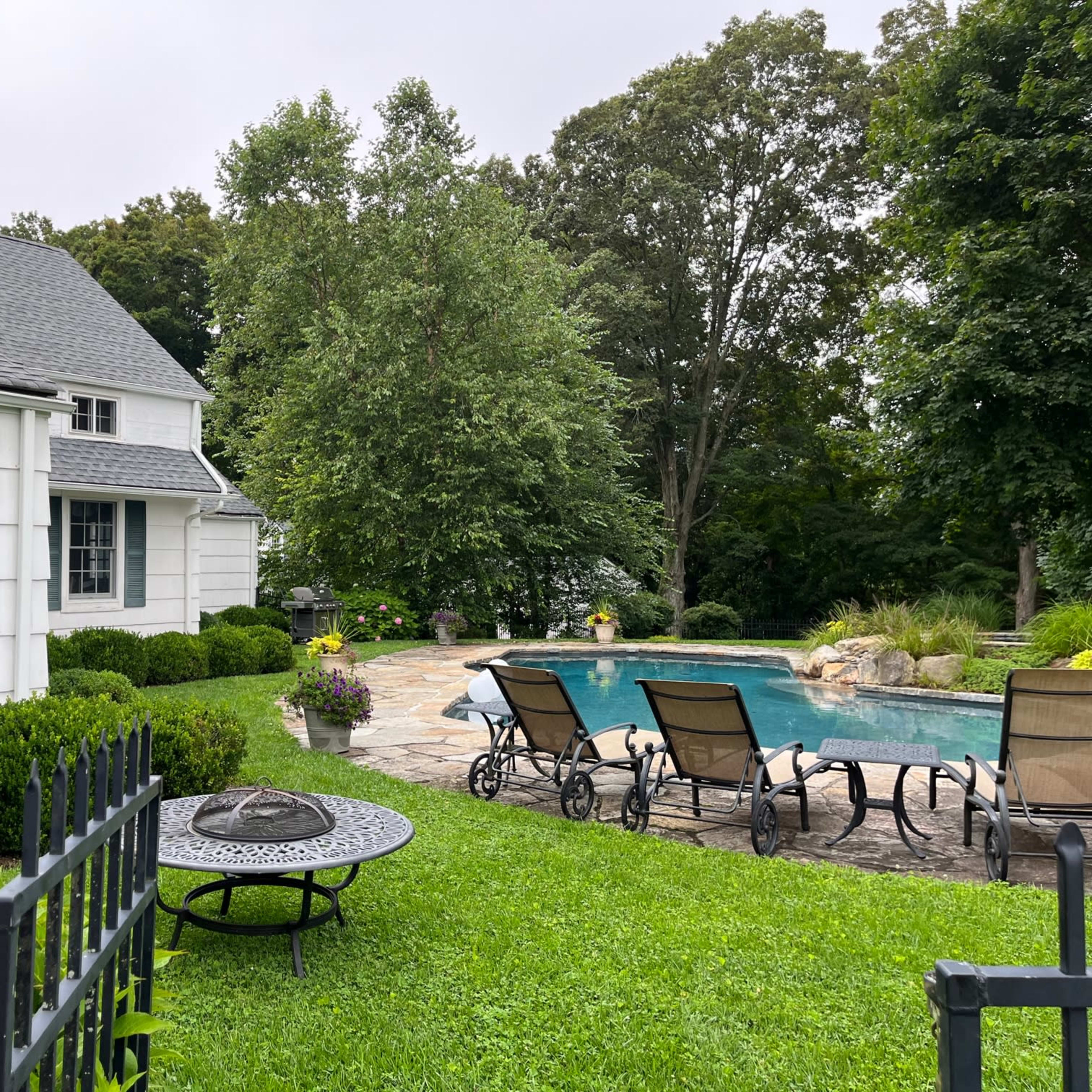 A well-maintained backyard features a swimming pool surrounded by lounge chairs and green landscaping.