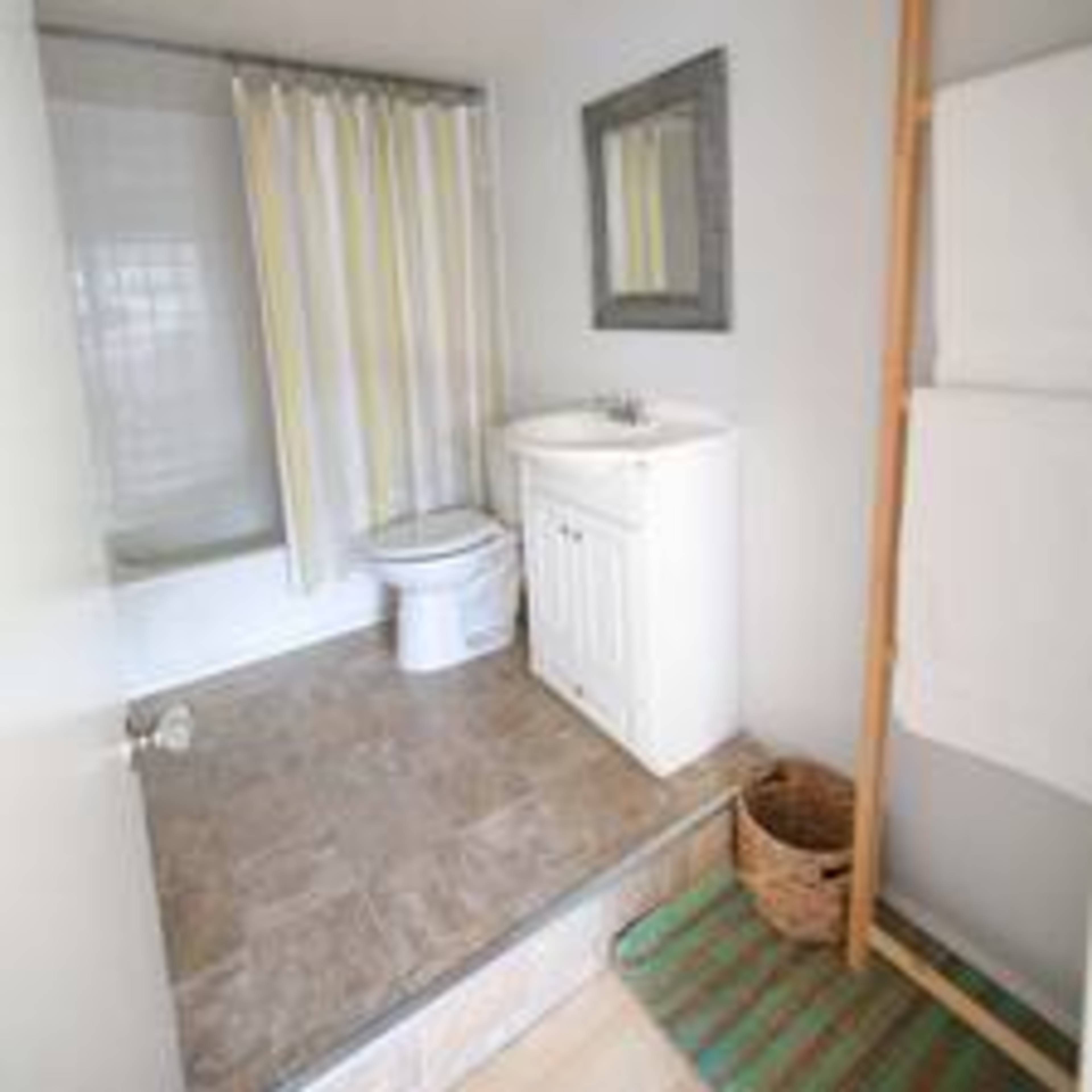 A clean, modern bathroom featuring a shower with a curtain, a toilet, a sink with a cabinet, a mirror, and neatly arranged towels.