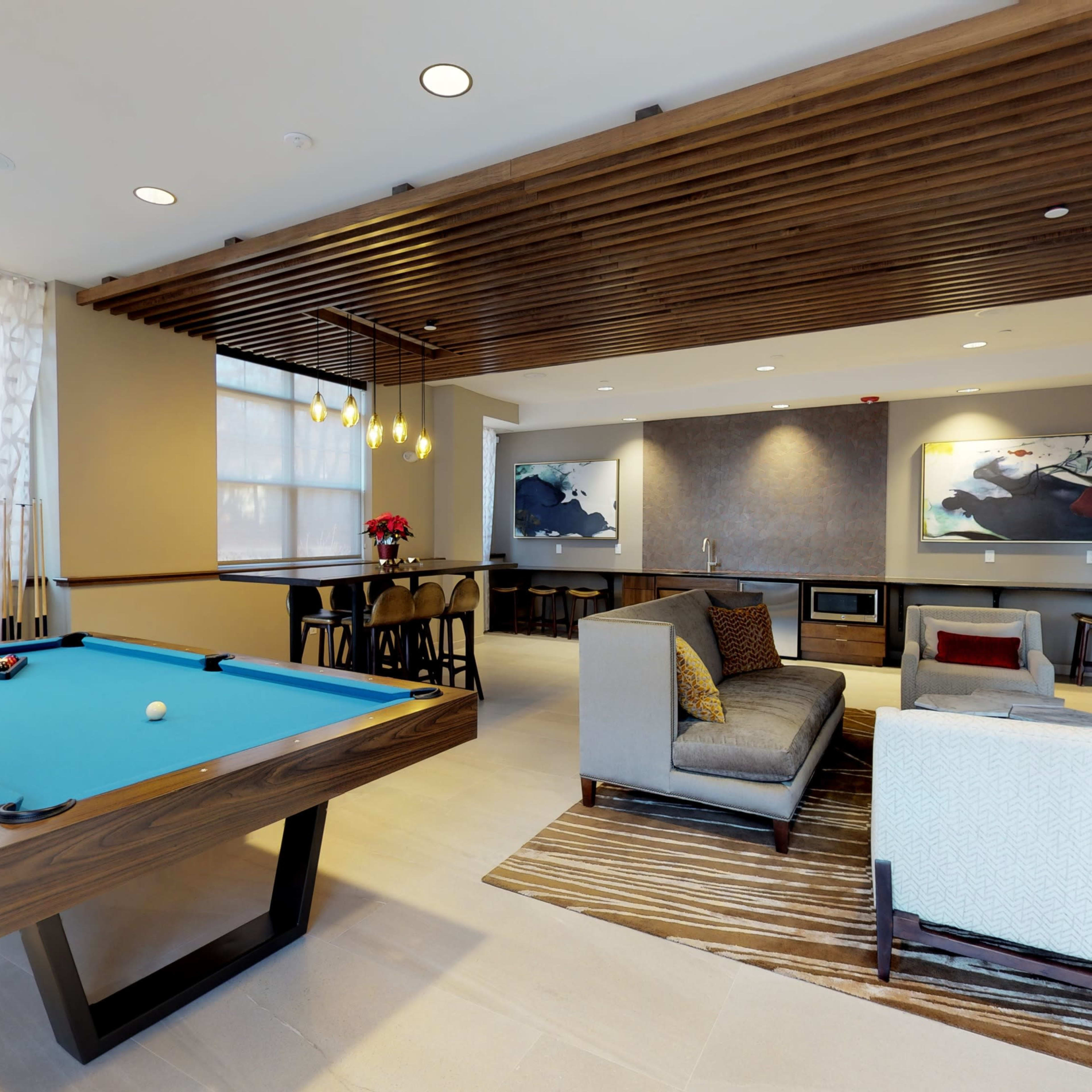 A contemporary lounge area featuring a billiard table, a cozy seating arrangement, and artwork on the walls.