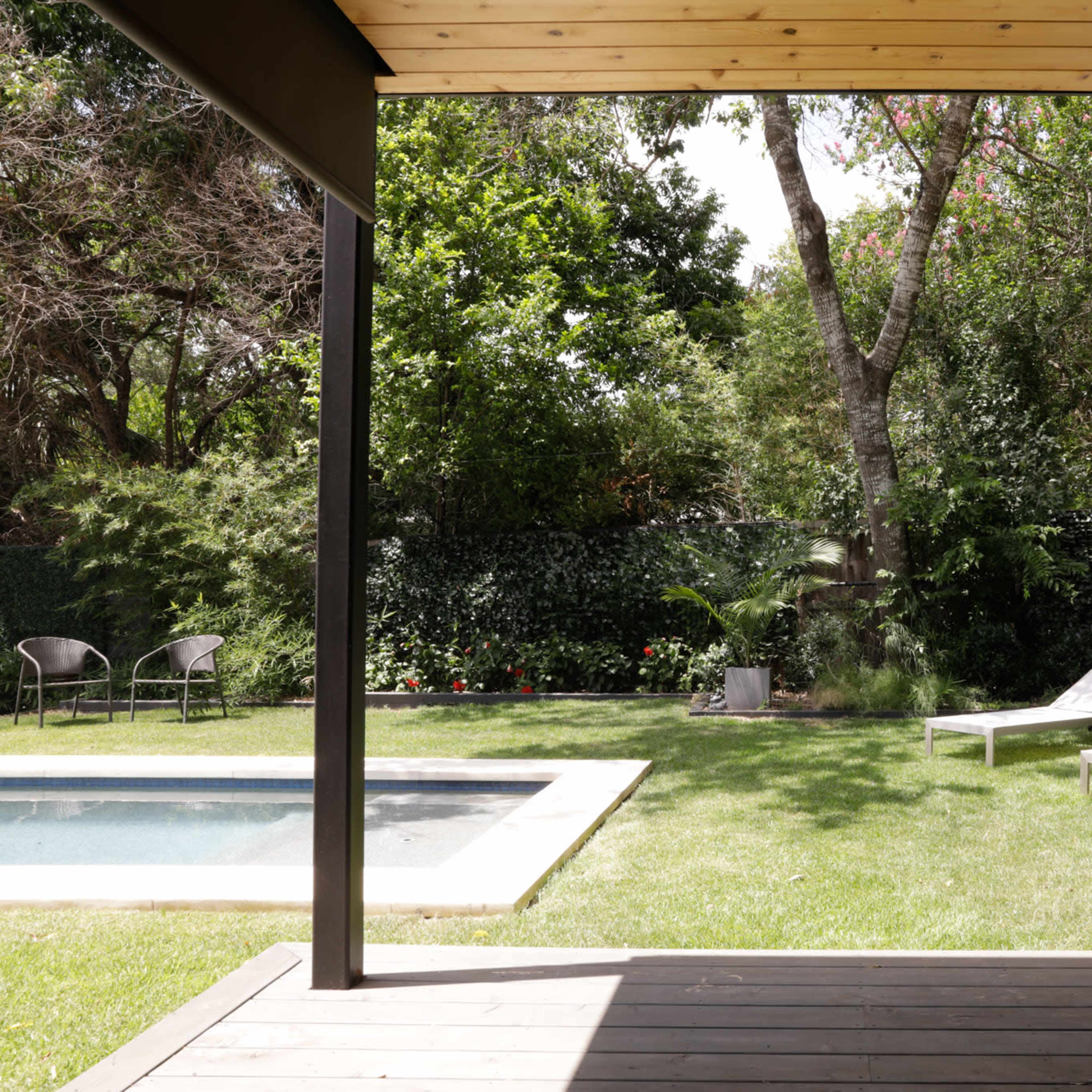 A well-maintained backyard featuring a swimming pool, two lounge chairs, and lush greenery surrounding the area.