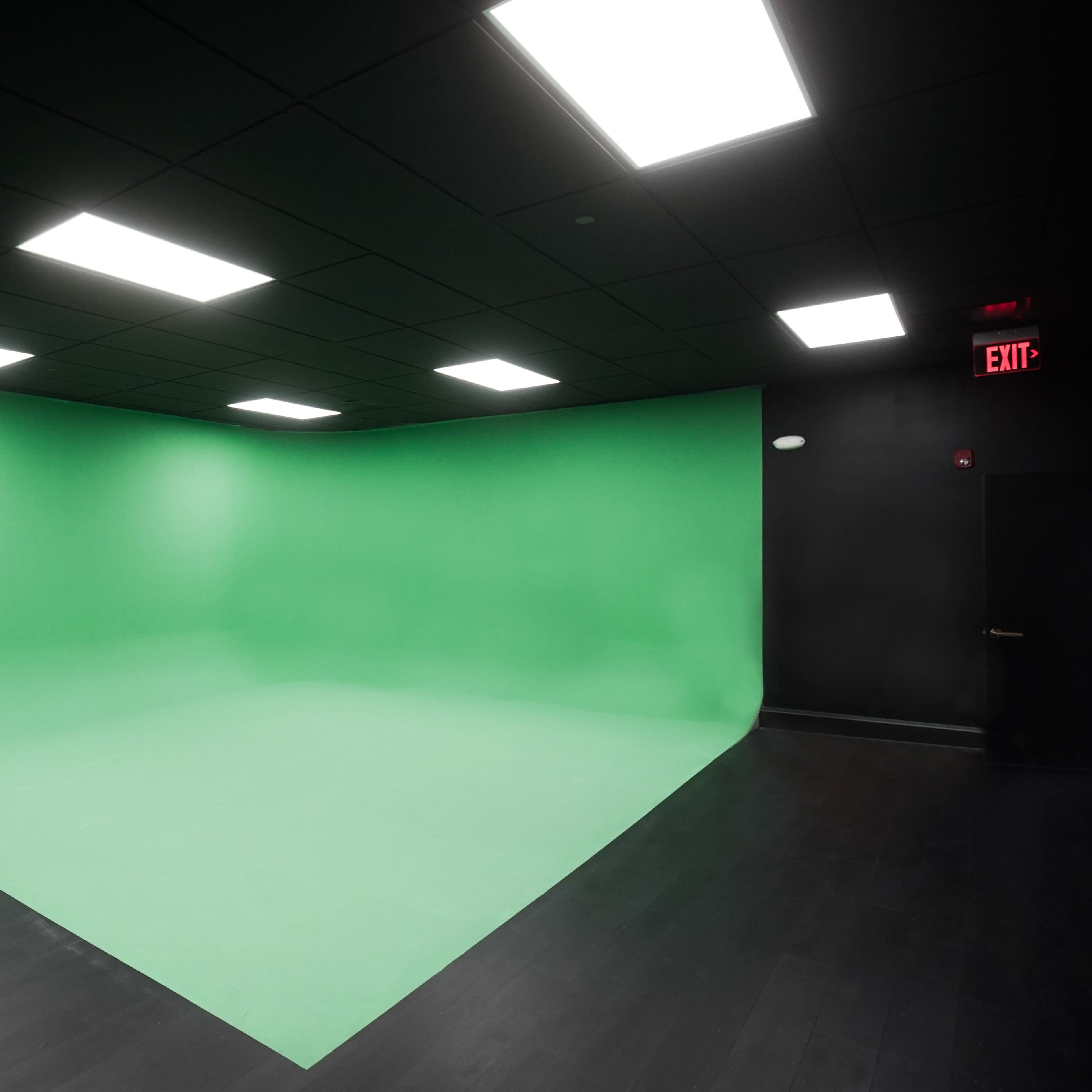 A green screen setup in a dark room with overhead lights.