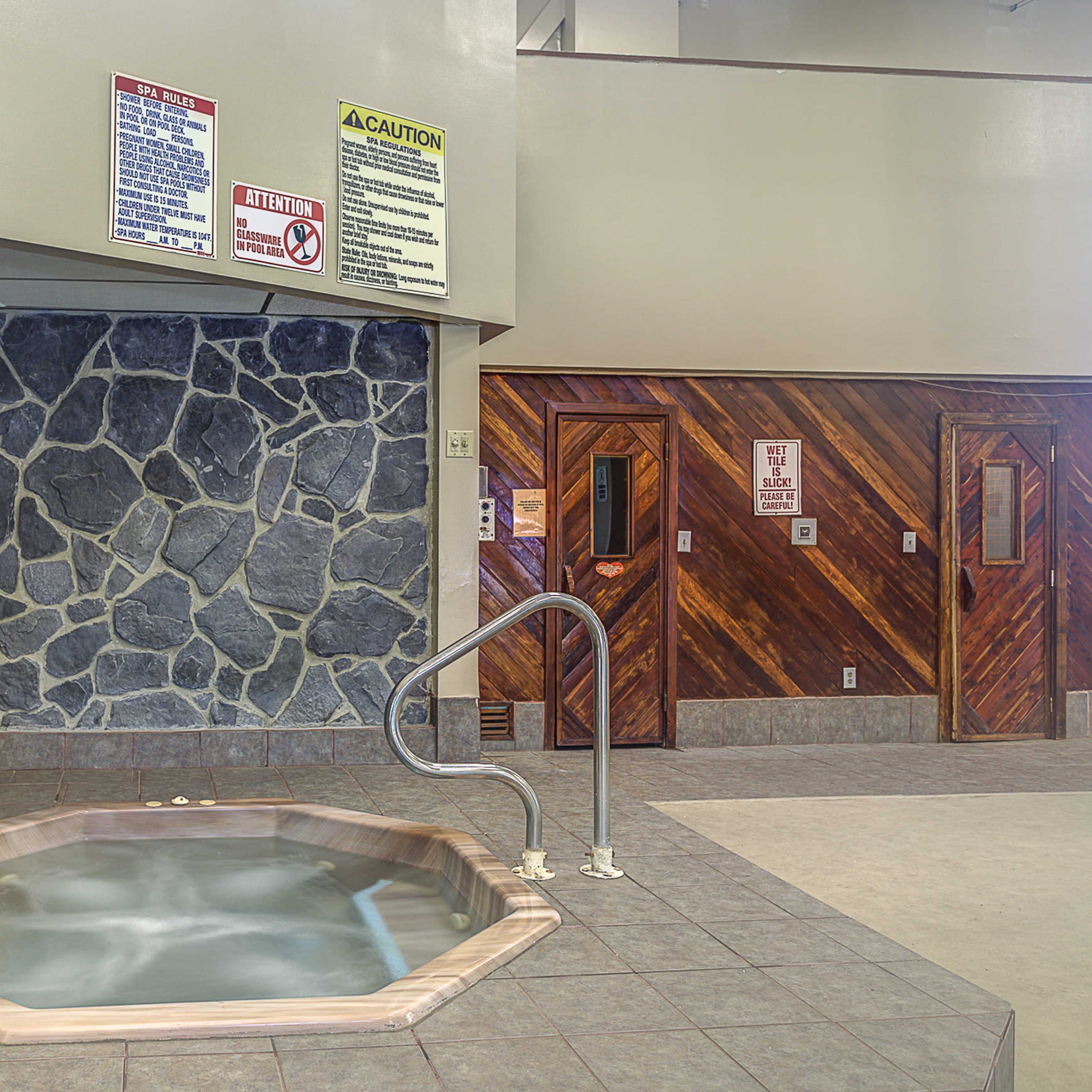 A small, octagonal hot tub surrounded by stone walls and wooden paneling, with caution signs posted nearby.