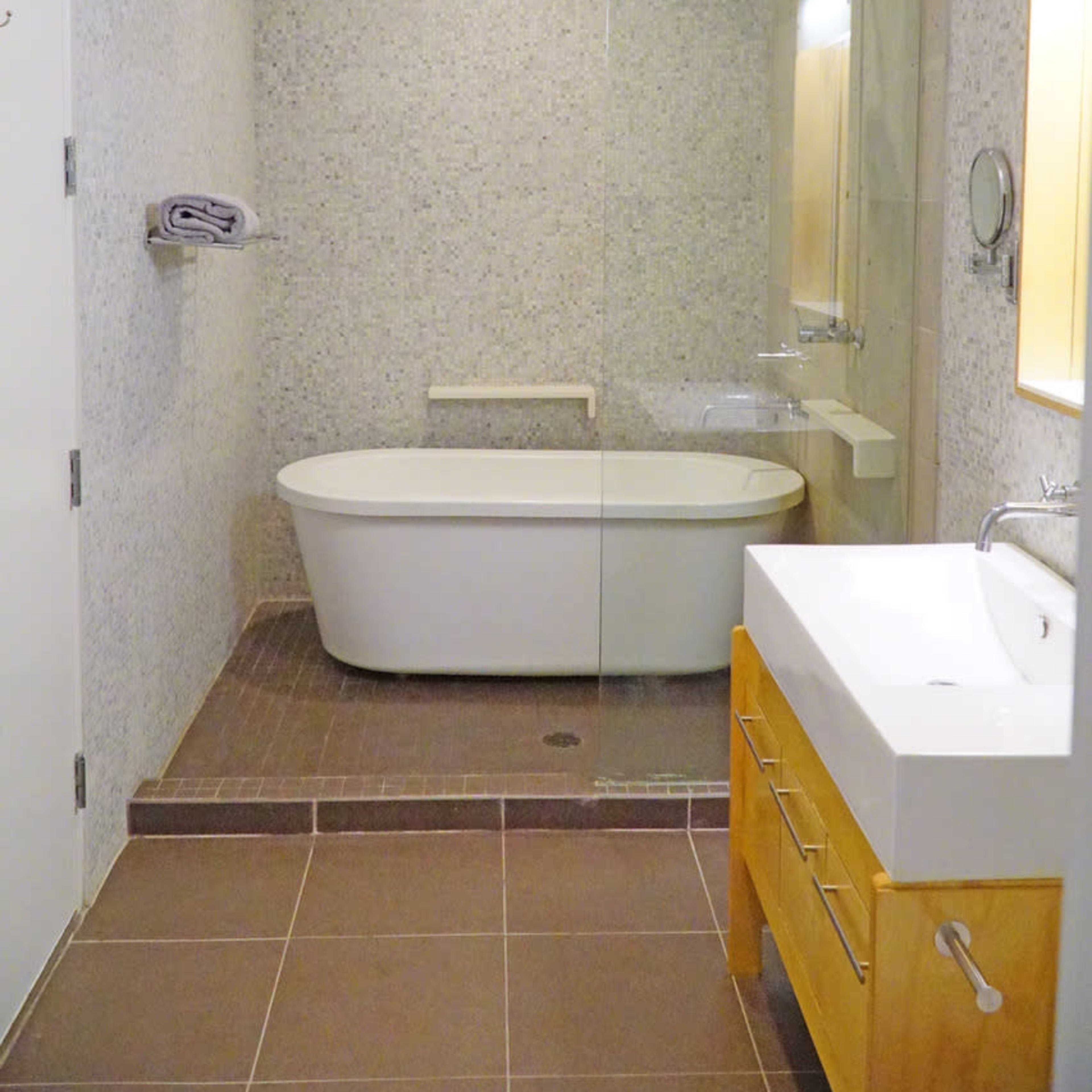 A modern bathroom featuring a freestanding tub, a glass shower enclosure, and a white sink with a wooden cabinet.