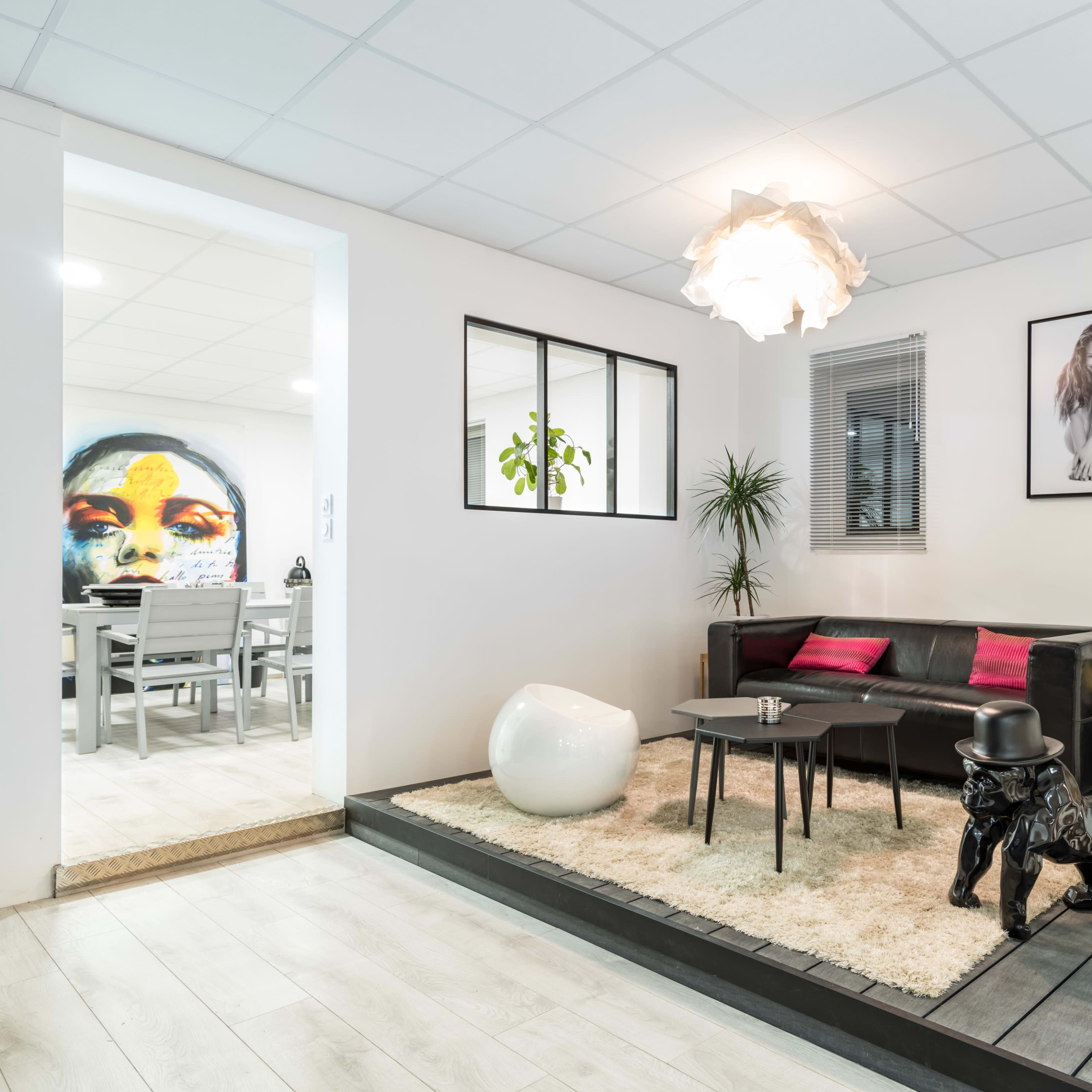 A modern living room with a black leather sofa, a round white coffee table, and a decorative black dog statue beside a light-colored rug.