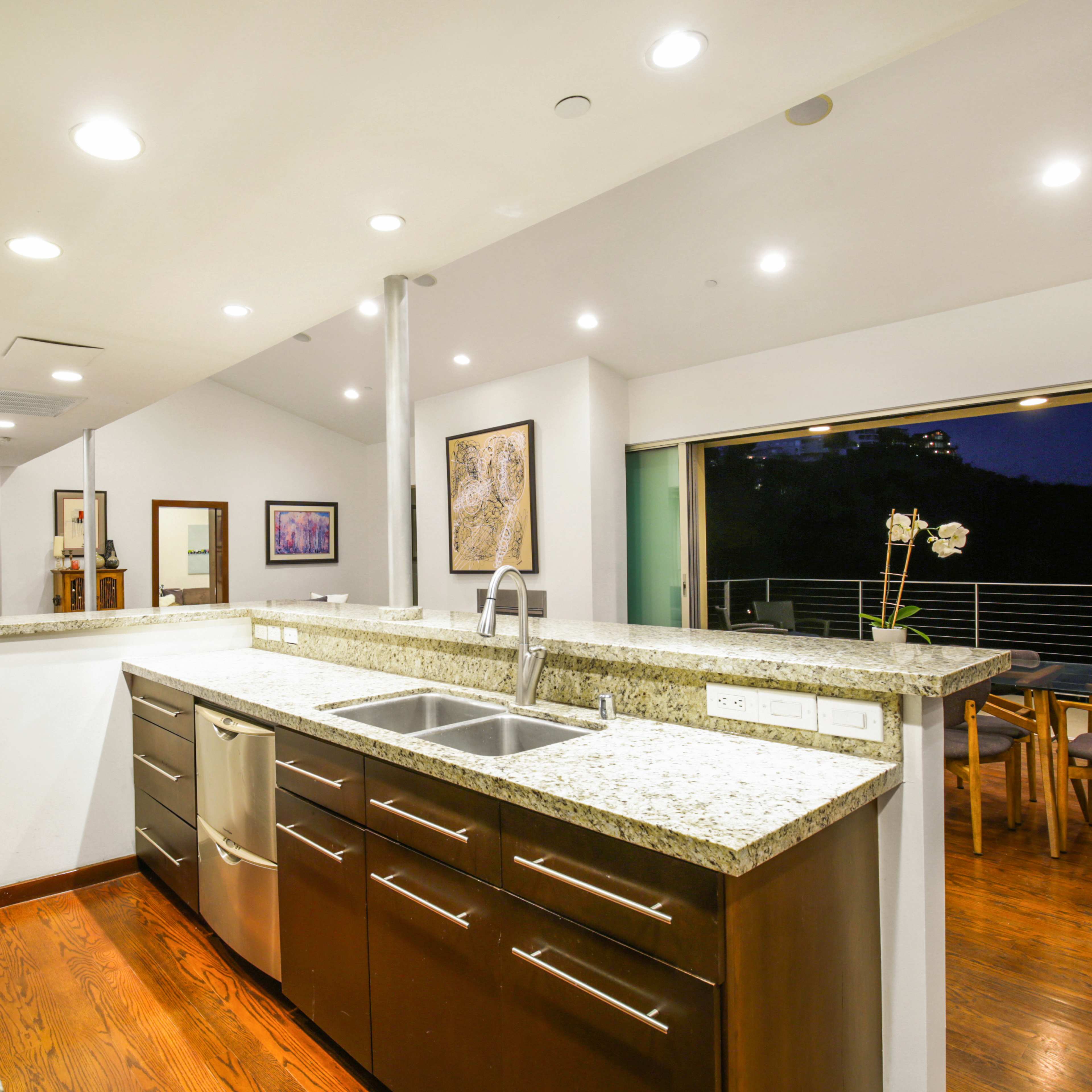 A modern kitchen with granite countertops, stainless steel appliances, and an open layout that connects to an outdoor dining area.