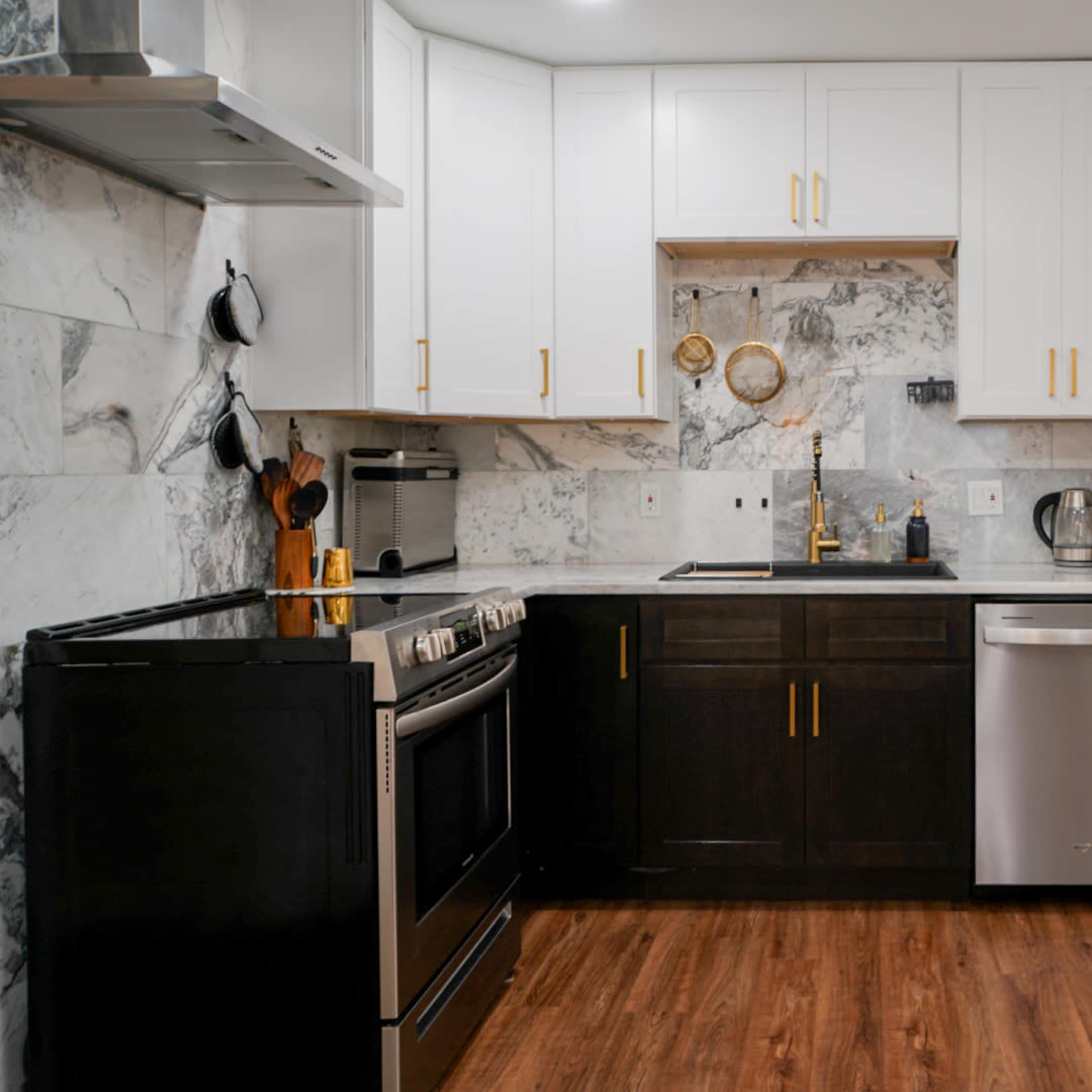 A modern kitchen featuring a combination of dark and light cabinetry, a stainless steel fridge, and a marble backsplash.