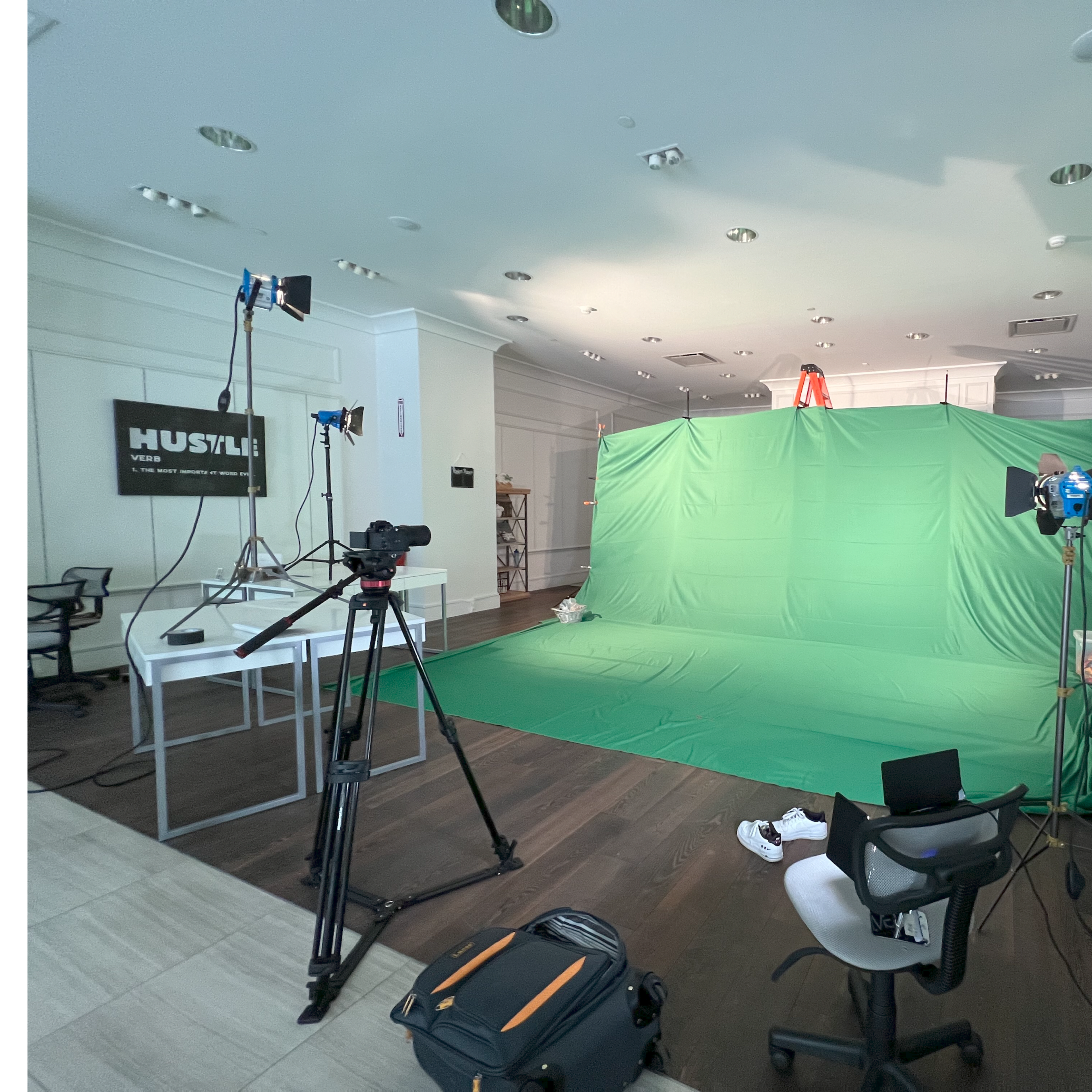 A green screen setup is arranged in a spacious room with multiple cameras and lights positioned around it.