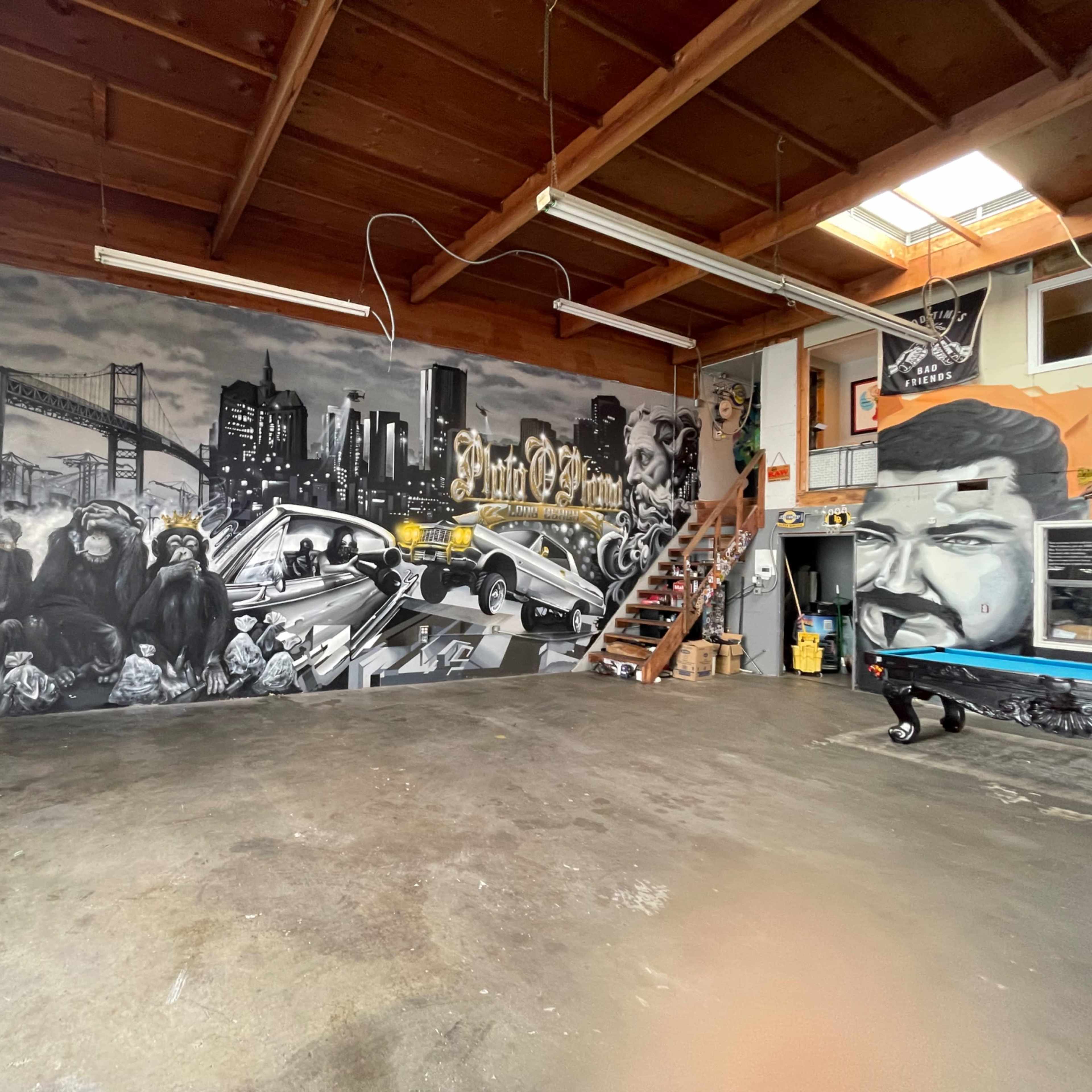 A spacious indoor area featuring a large mural of cityscape and primates on one wall, with stairs leading to an upper level.