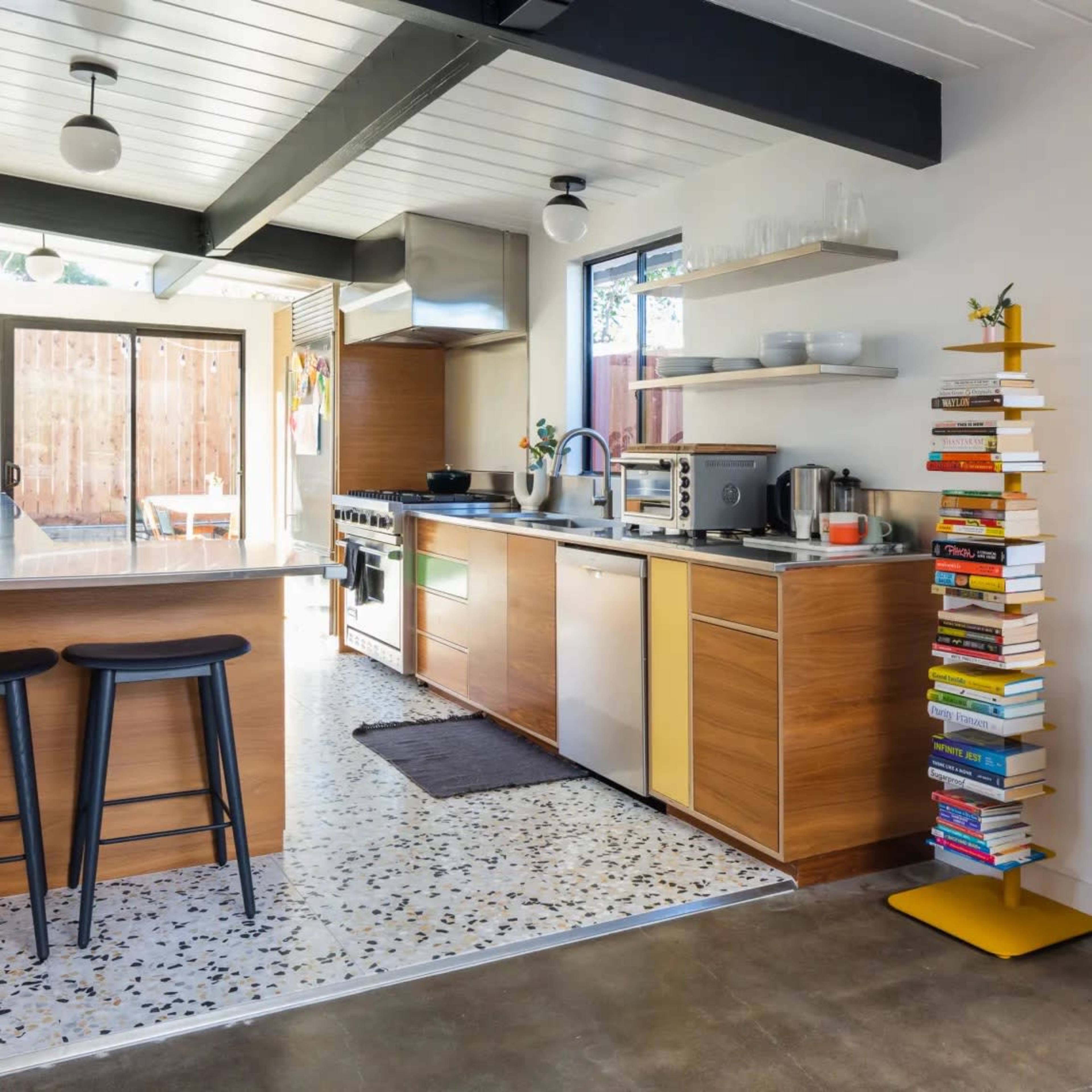 The kitchen features modern cabinetry, stainless steel appliances, and a decorative stack of books beside a counter with a view of an outdoor space.