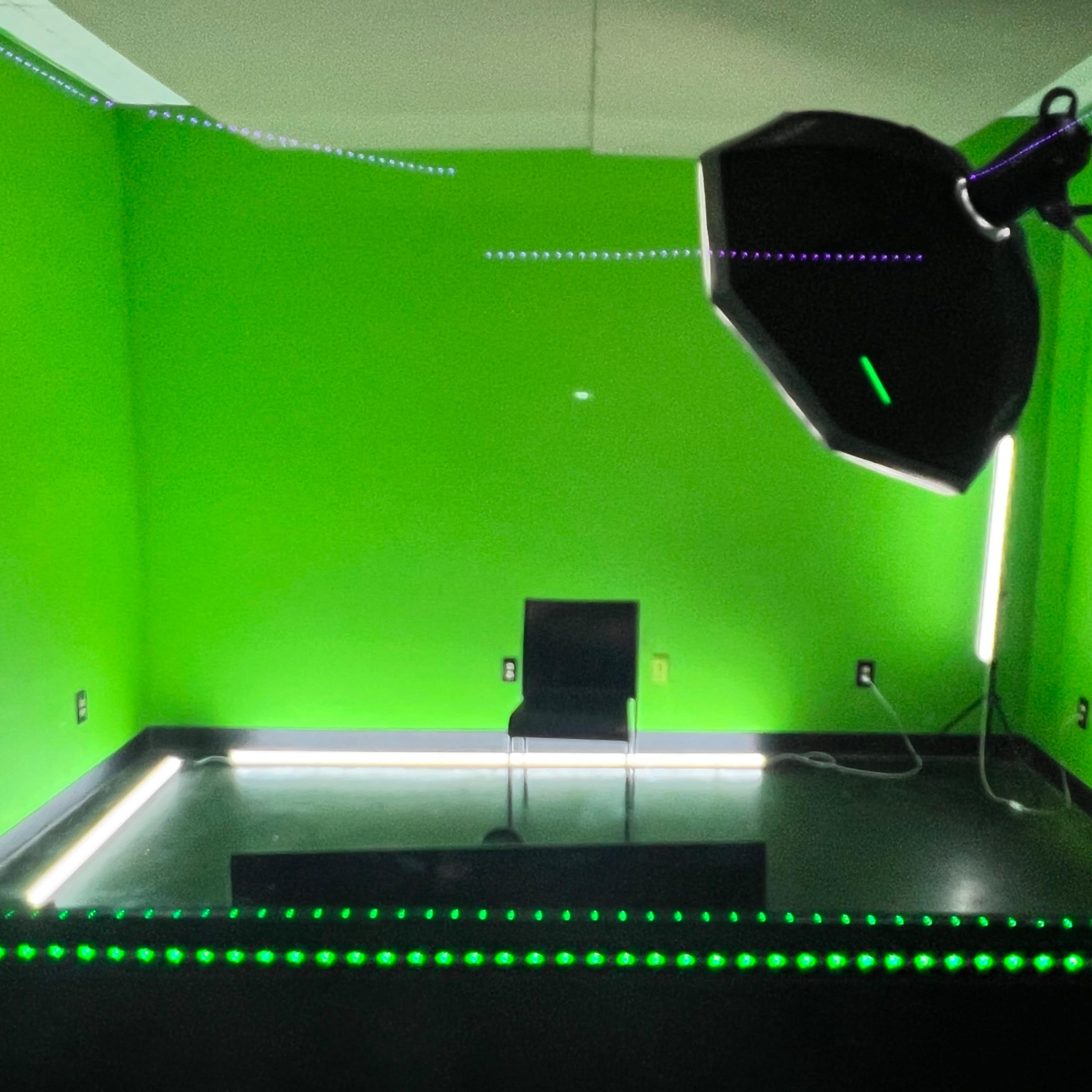 A small room with green walls, a single chair, and studio lighting equipment.