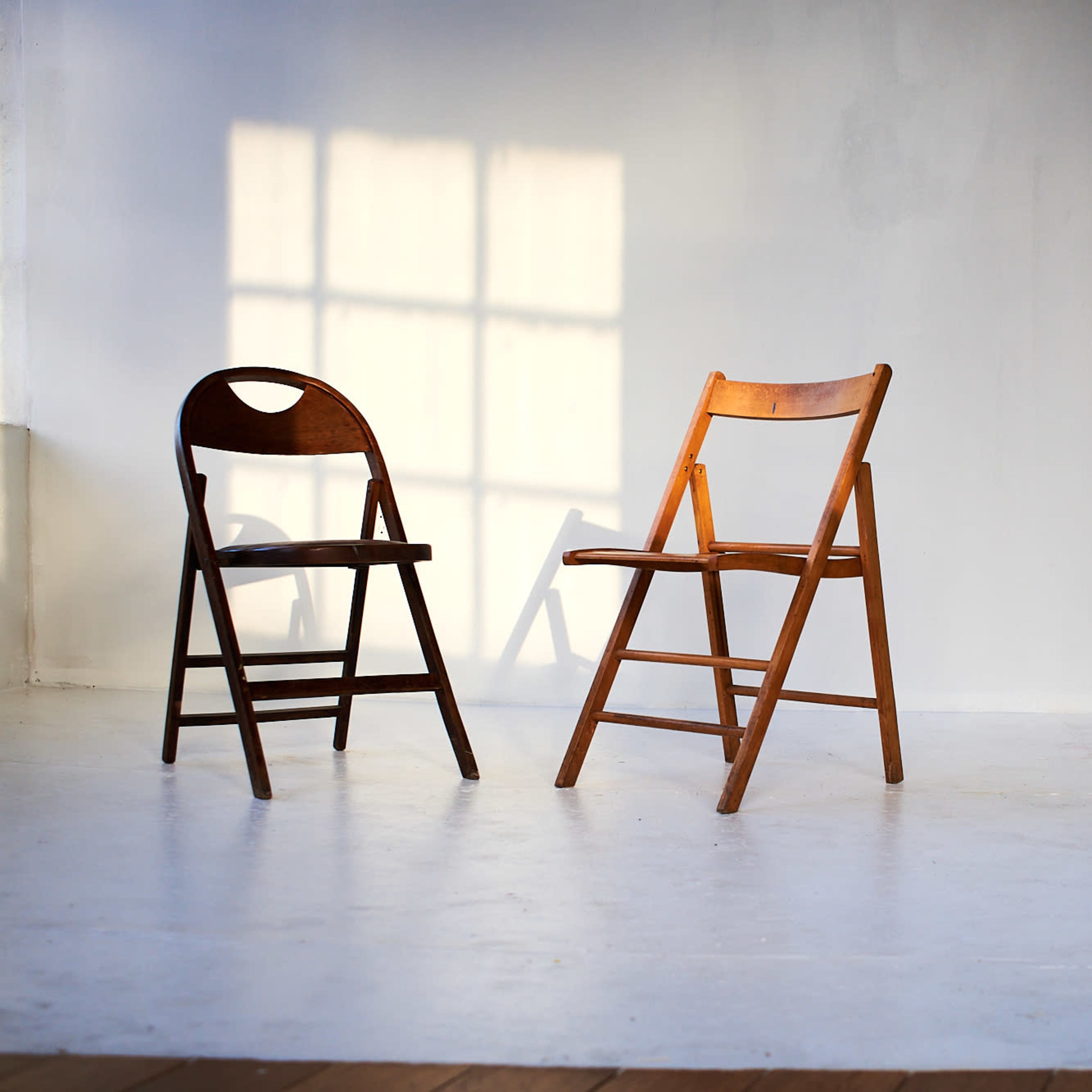 Two wooden folding chairs are positioned facing each other on a well-lit studio floor.