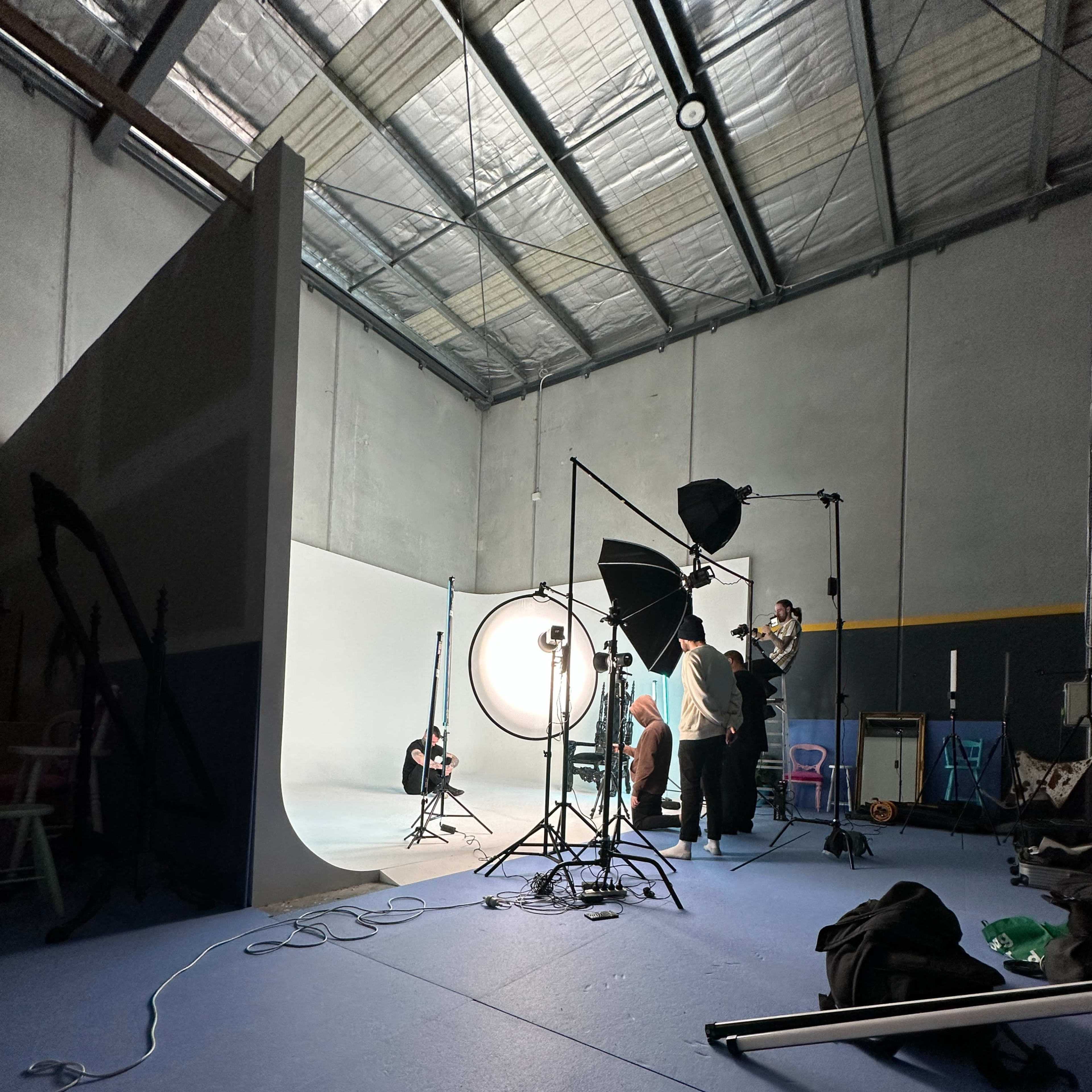 A photography studio is set up with several lights, backdrops, and individuals preparing for a photoshoot.