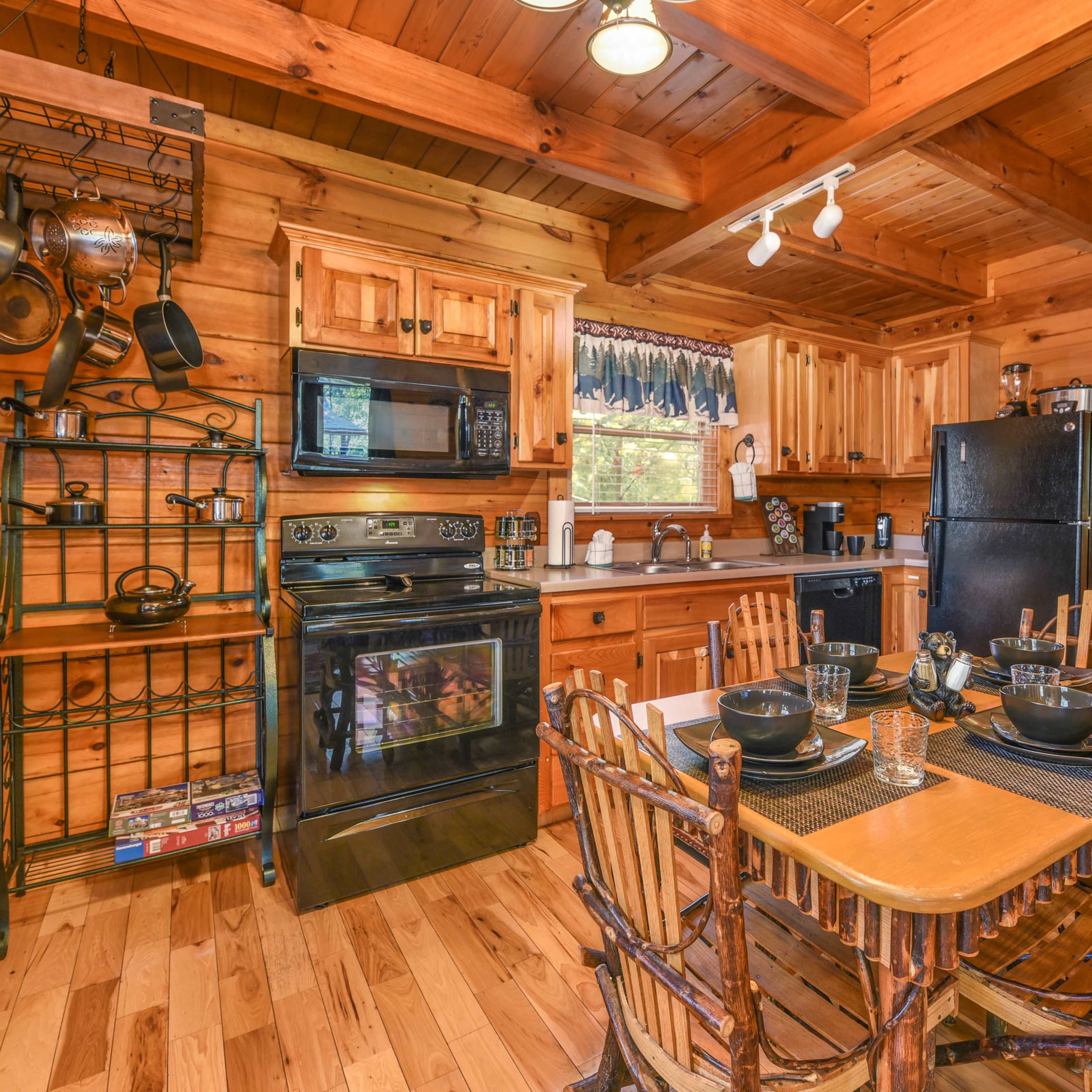A rustic wooden kitchen with a dining table set for four, complete with chairs, and equipped with a stove, refrigerator, and wooden cabinetry.