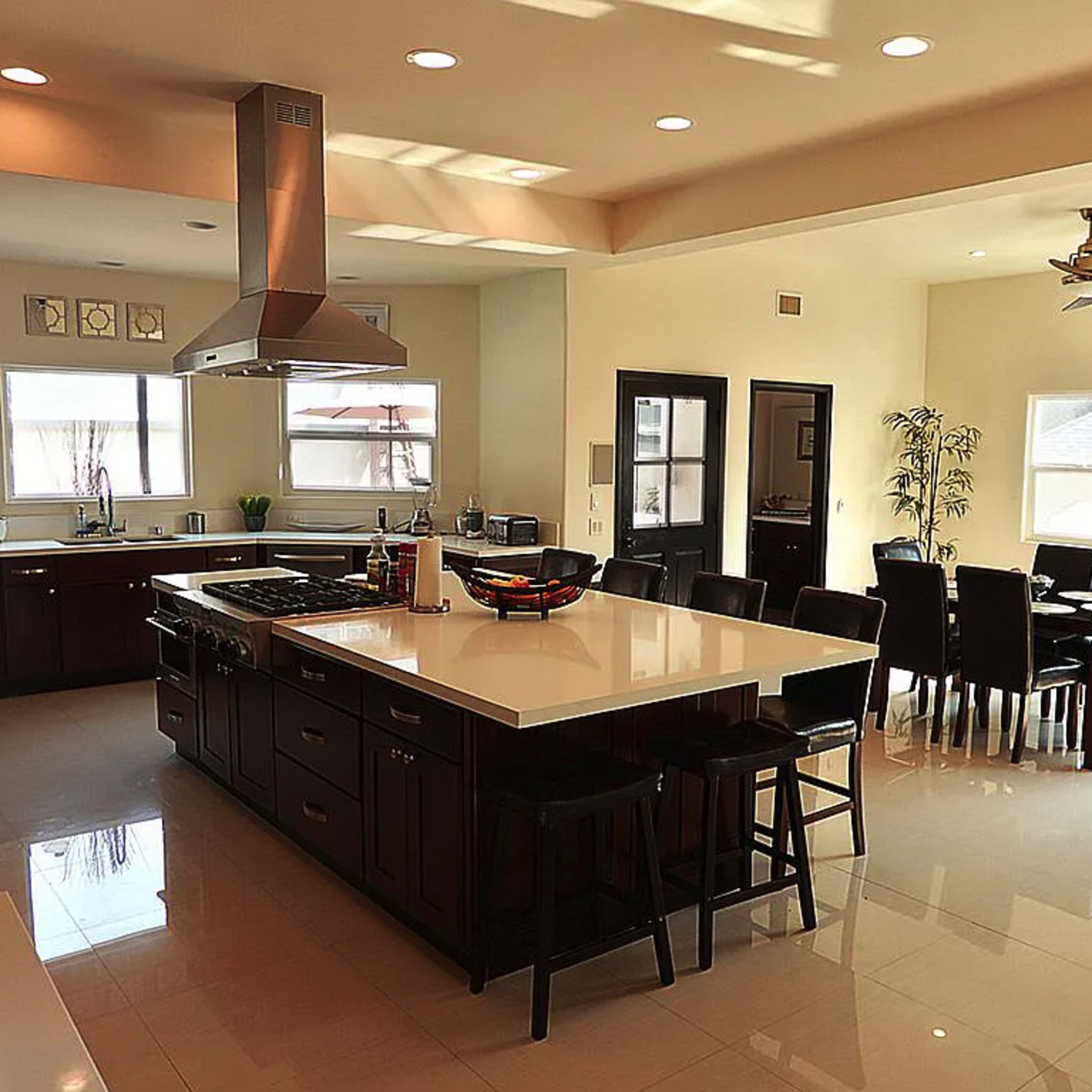A modern kitchen with an island, black cabinetry, and a dining area featuring a circular table and chairs.