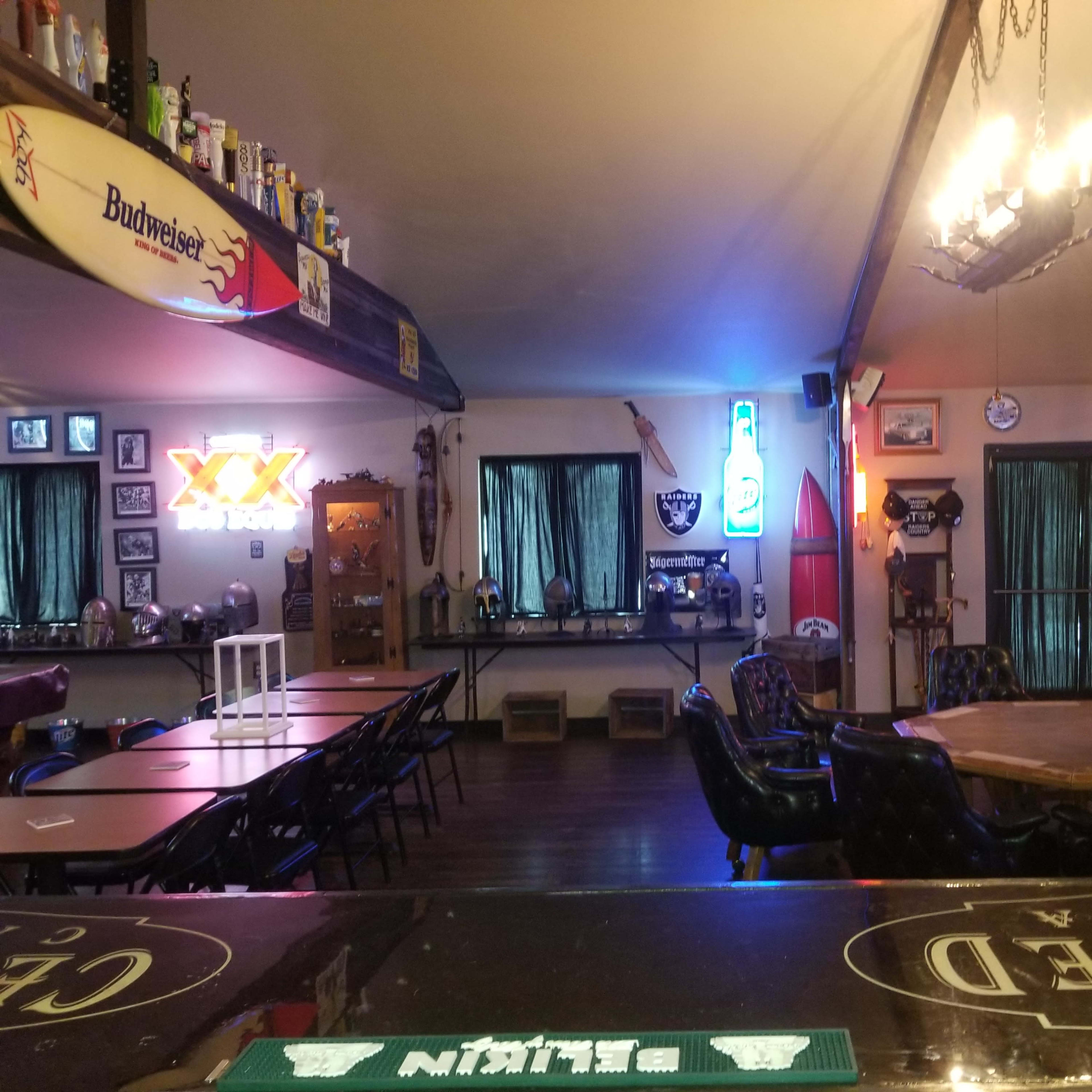 An interior of a bar with various neon lights, tables, and chairs arranged in a cozy layout.