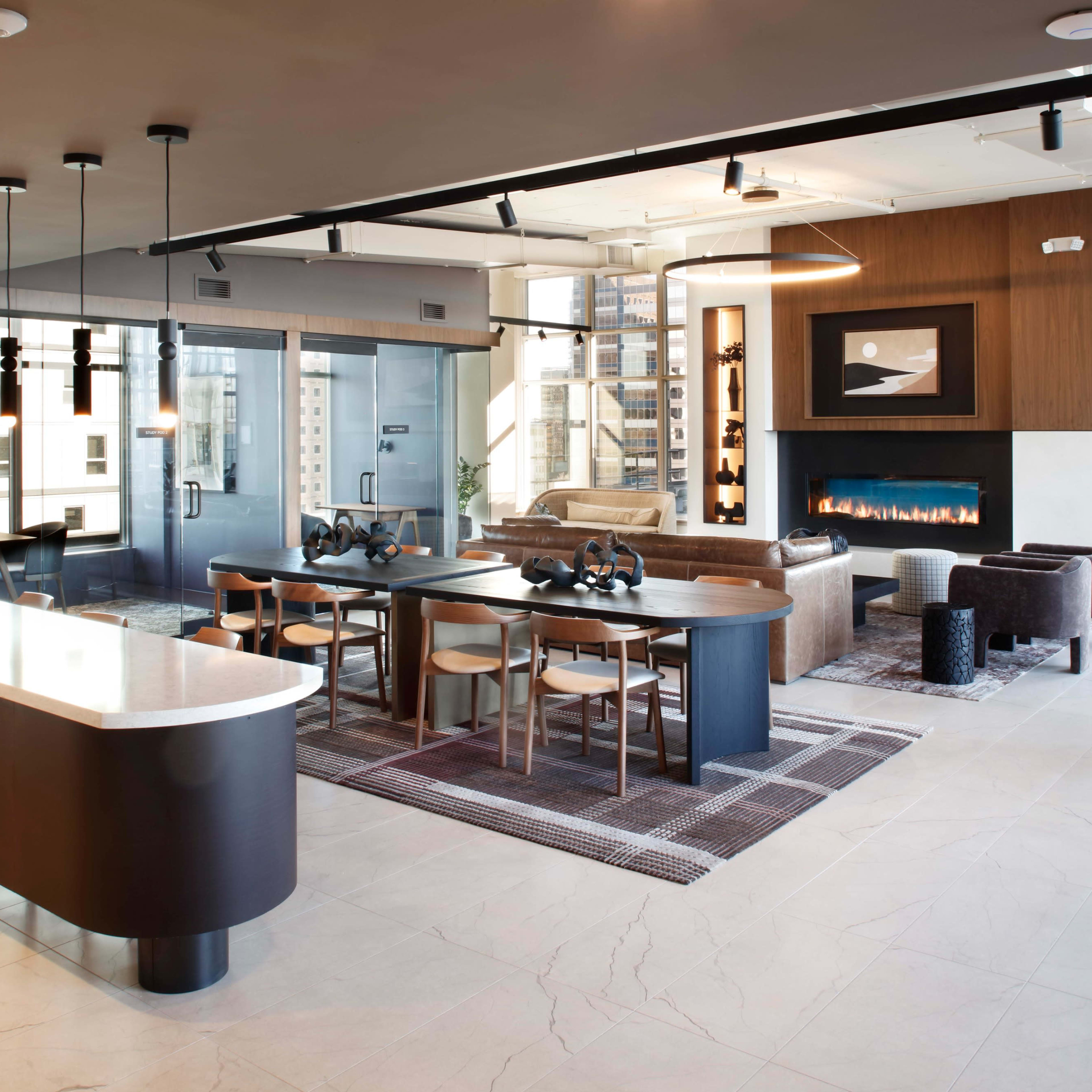 A modern living space featuring a dining area, a seating arrangement by a fireplace, and large windows with city views.