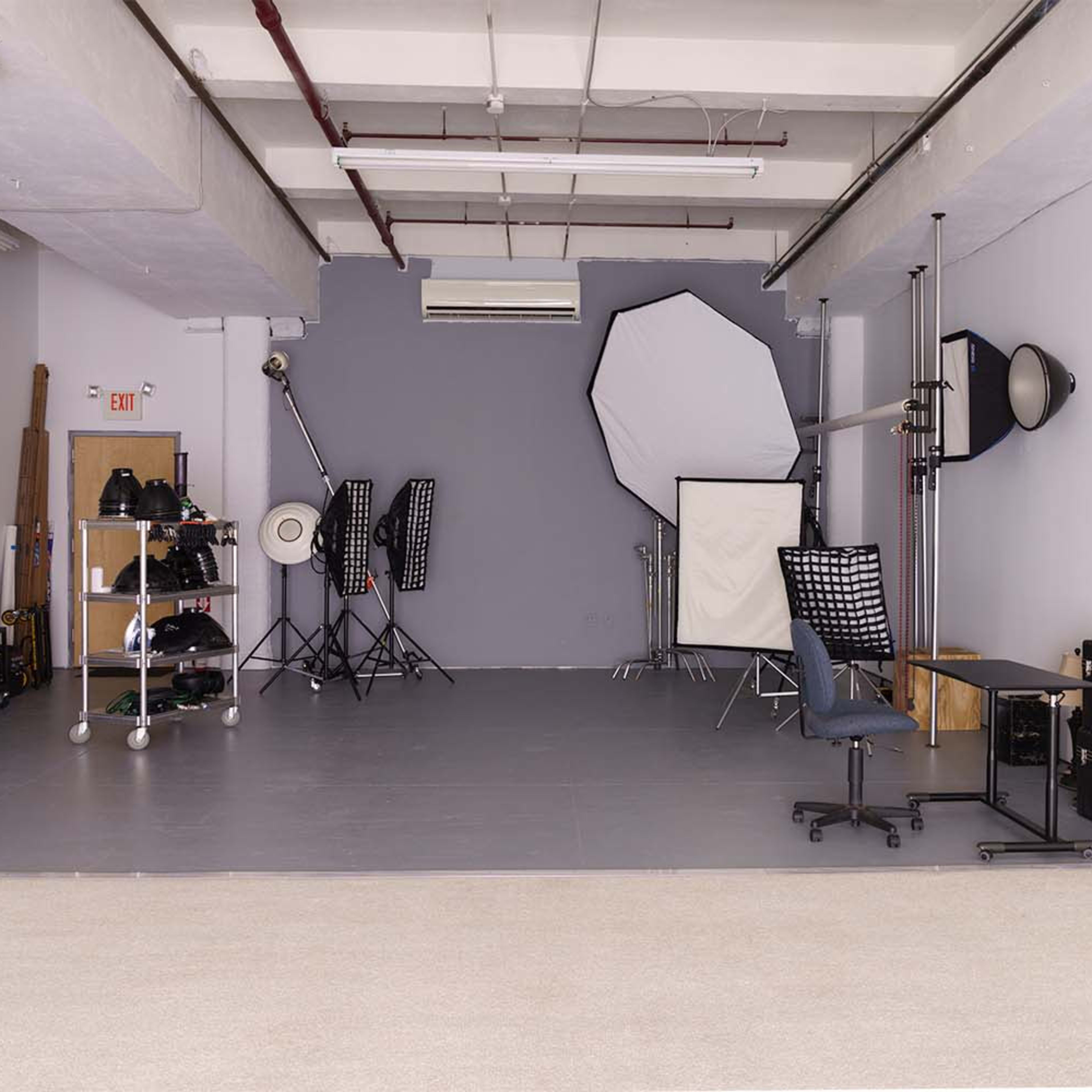 A spacious photography studio with various lighting equipment, backdrops, and storage cases.