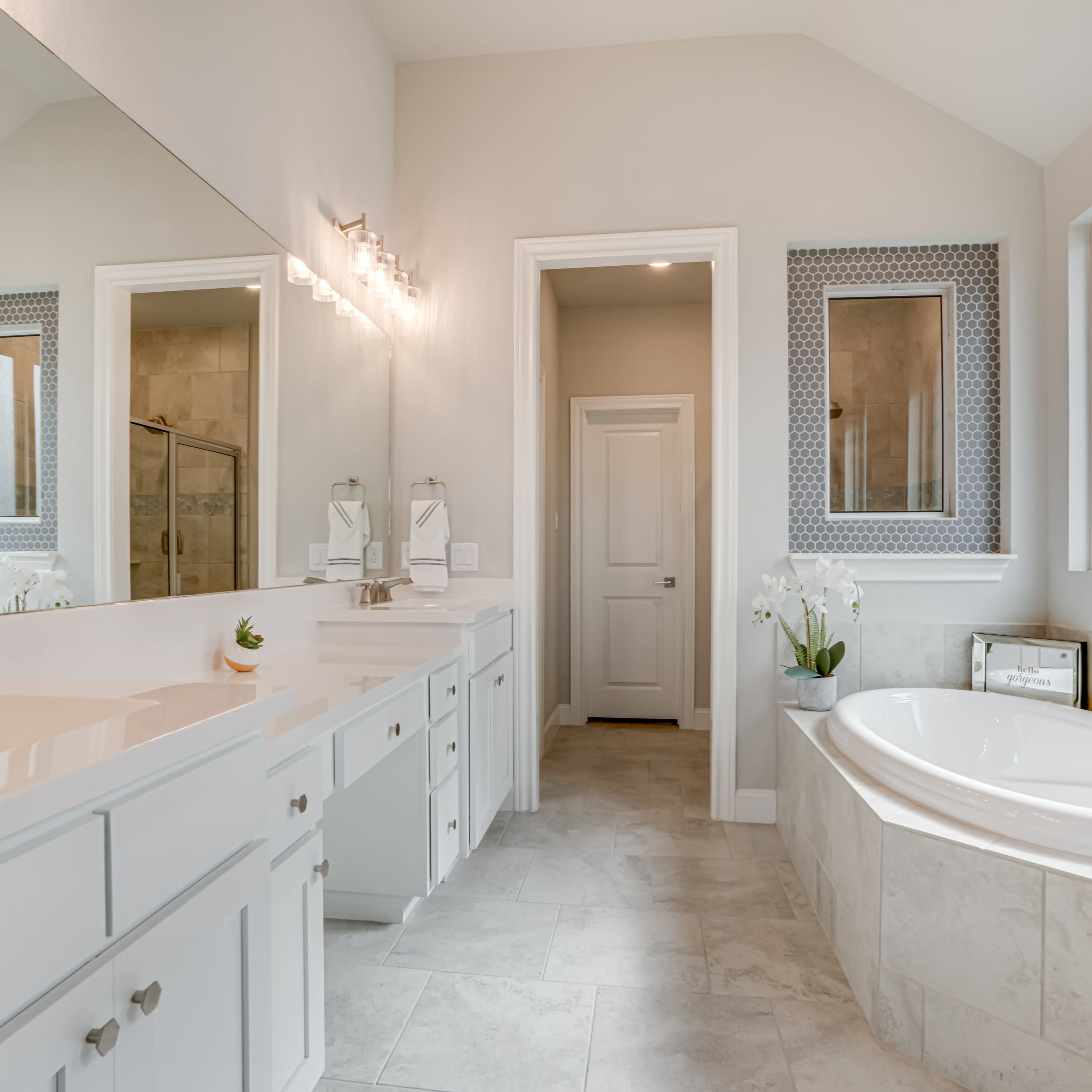 A spacious bathroom featuring a double vanity, a soaking tub, and a walk-in shower.