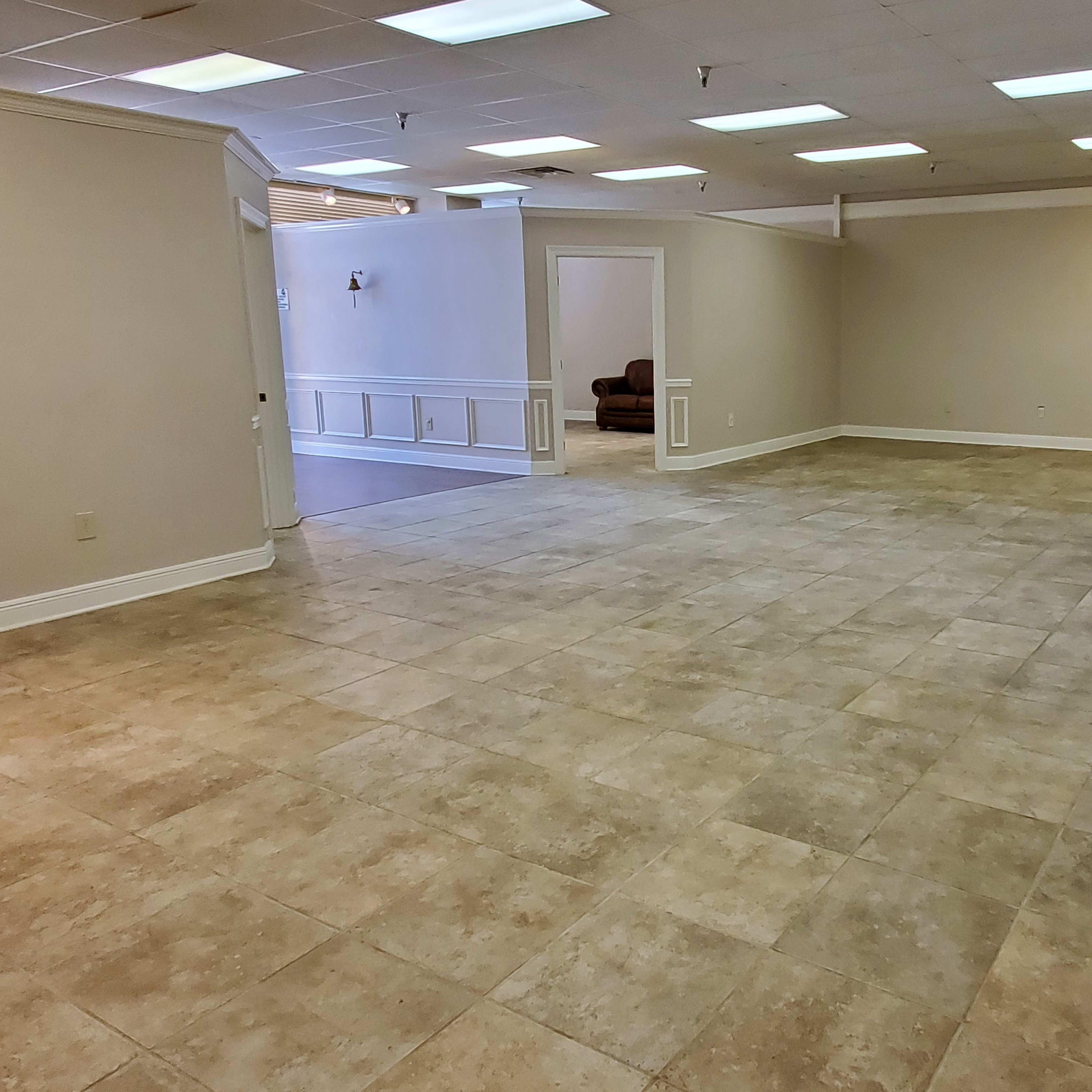 An empty room with tiled flooring, neutral-colored walls, and multiple overhead lights.