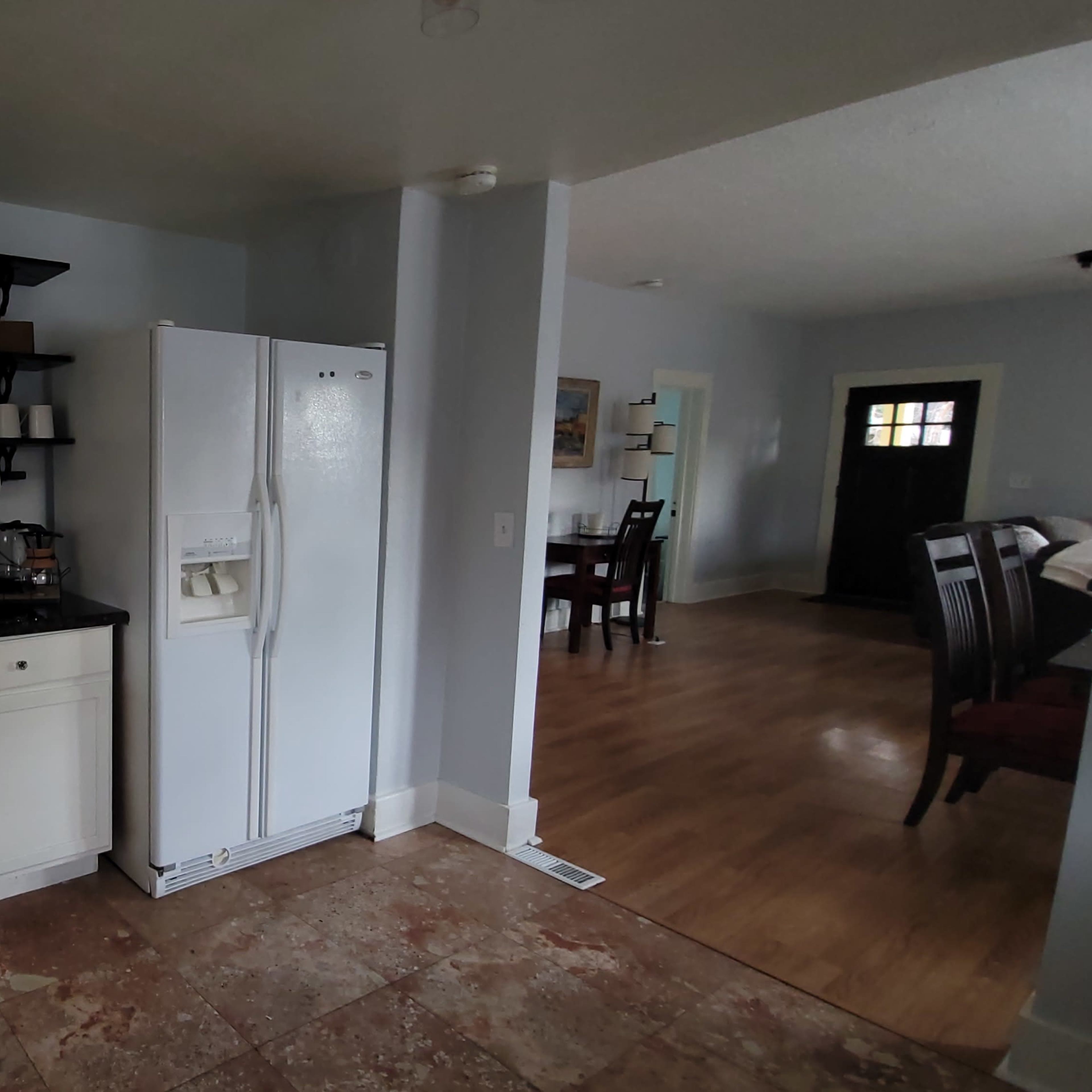 A kitchen with a white refrigerator, stove, microwave, and a small dining area visible in the background.