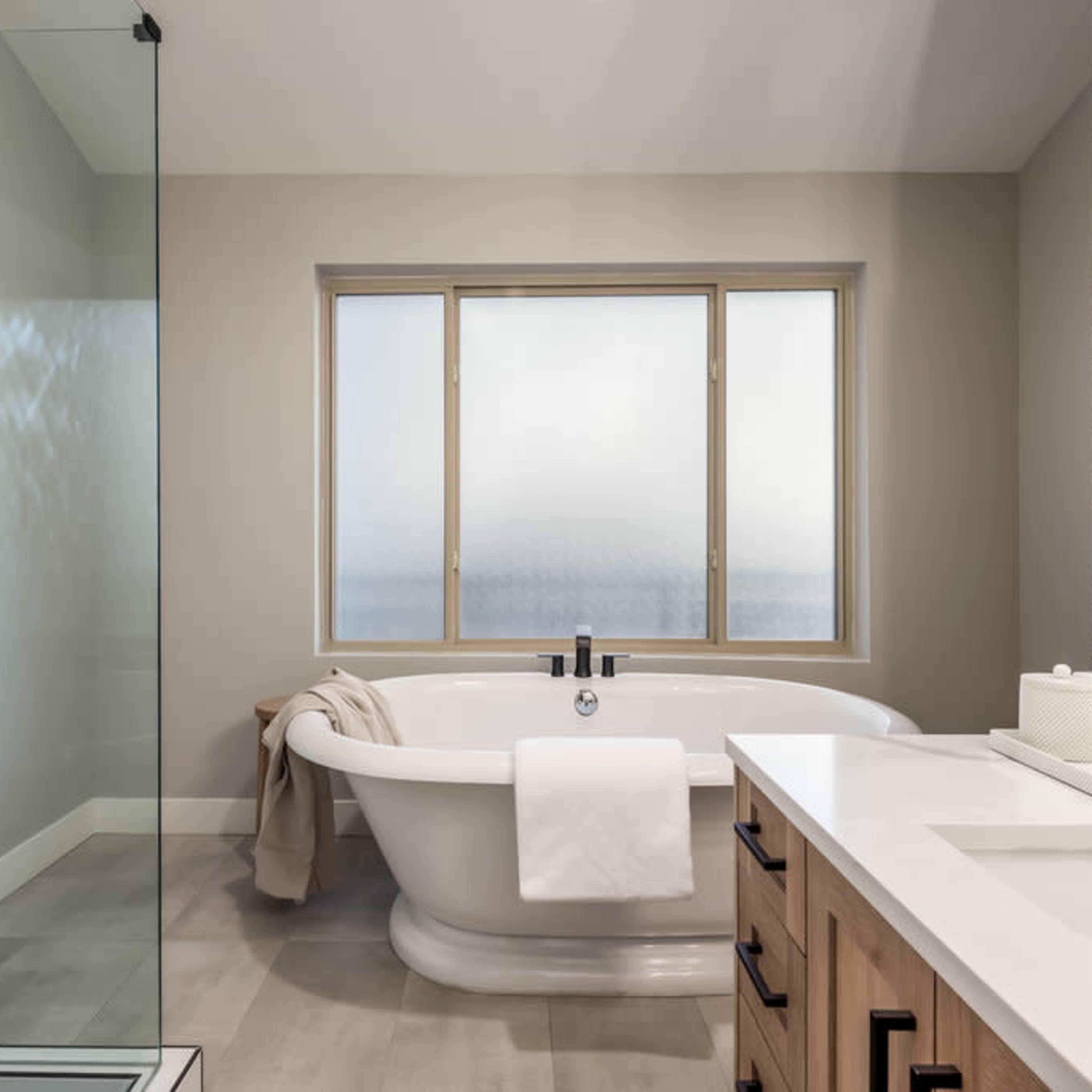 A modern bathroom features a freestanding bathtub beside a glass shower and a dual-sink vanity.