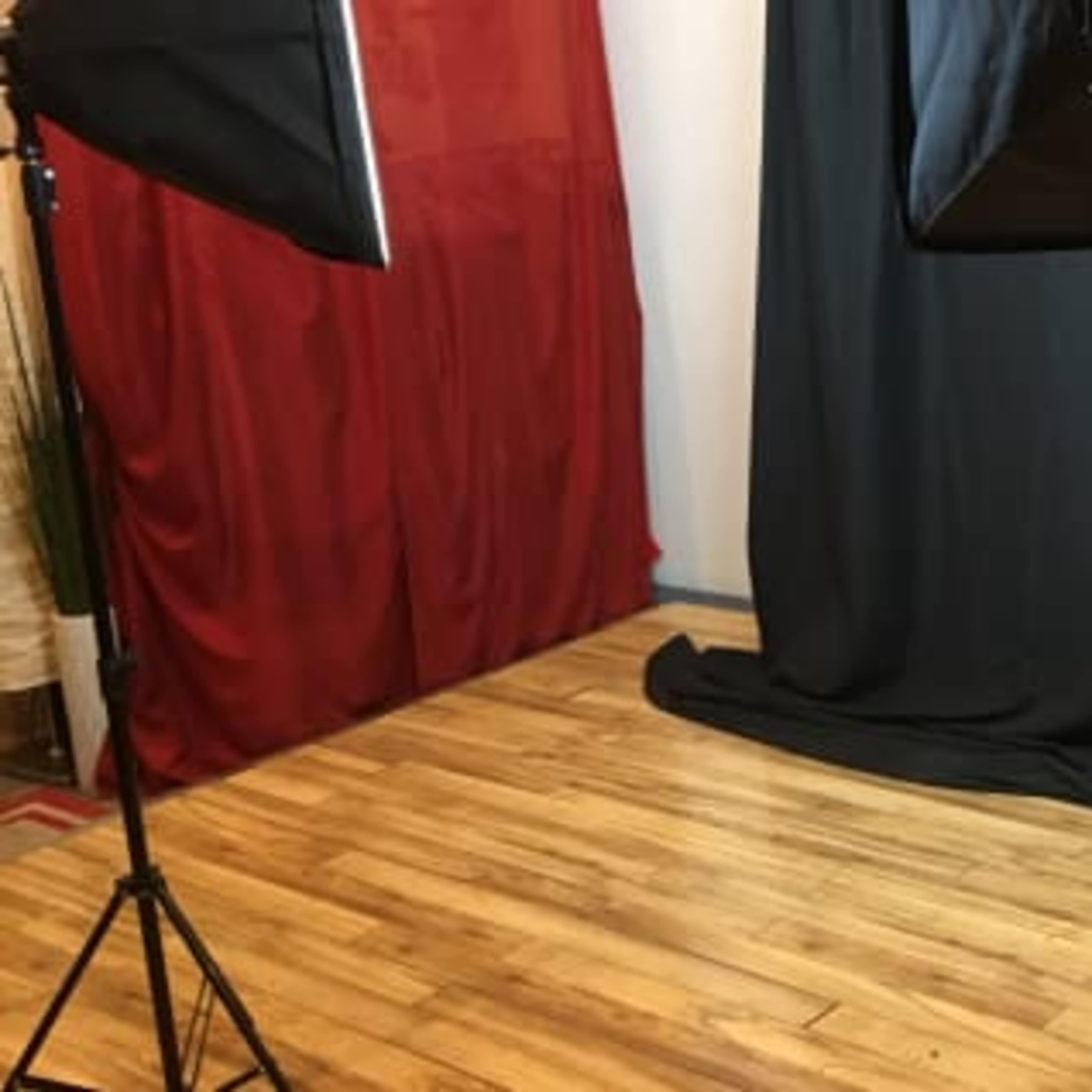 A photography setup with lighting equipment and a black backdrop on a wooden floor.